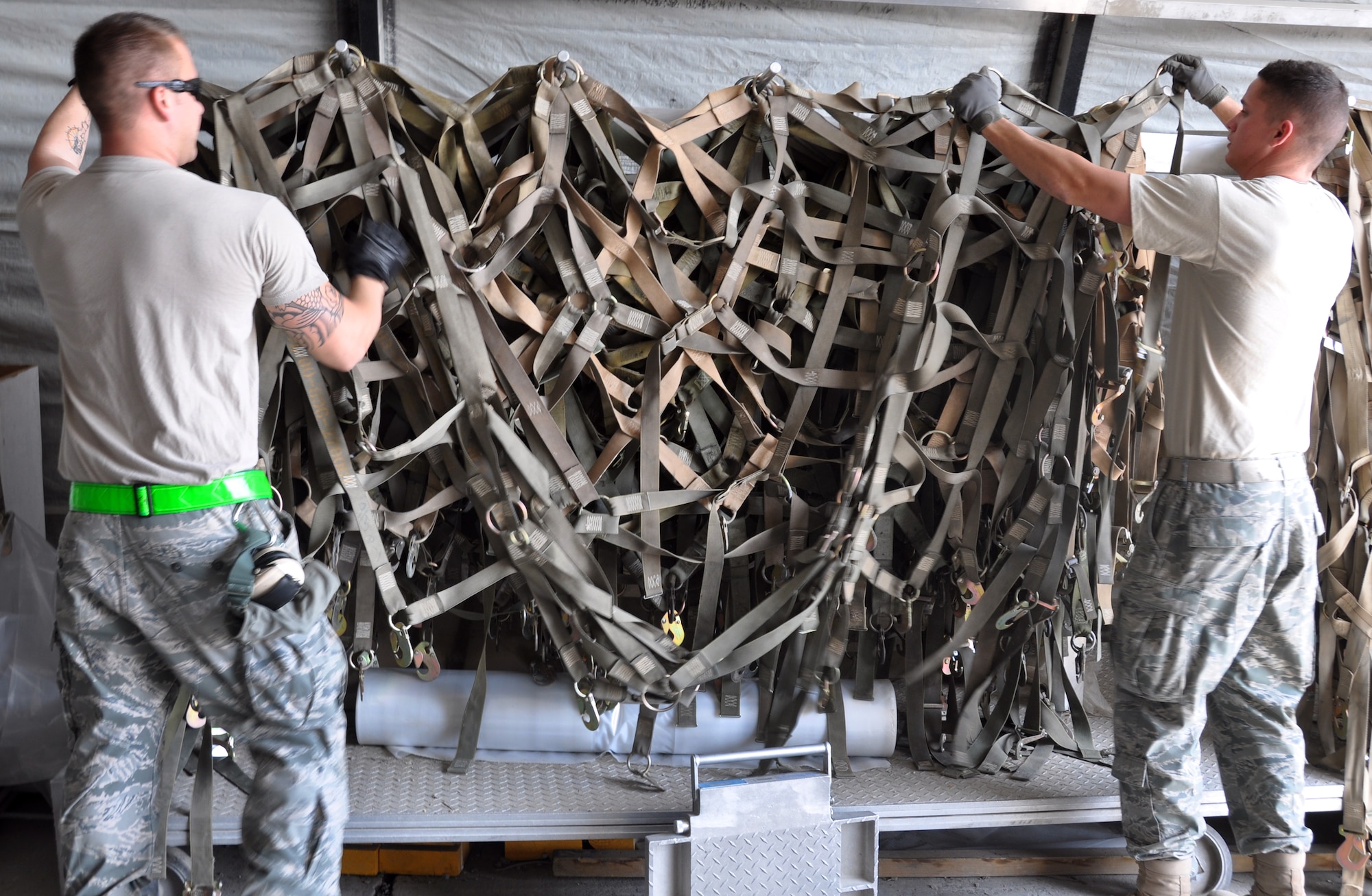 Senior Airman Justin Emerson and Senior Airman Micah Hazelip, 60th Aerial Port Squadron aerial porters, hang up cargo nets at the passenger terminal on Bagram Airfield Apr. 12. After an airplane full of Soldiers and their baggage have been moved through the terminal, the cargo nets that once held the baggage to the pallets must be stored properly to keep them out of the way, and from getting tangled up.