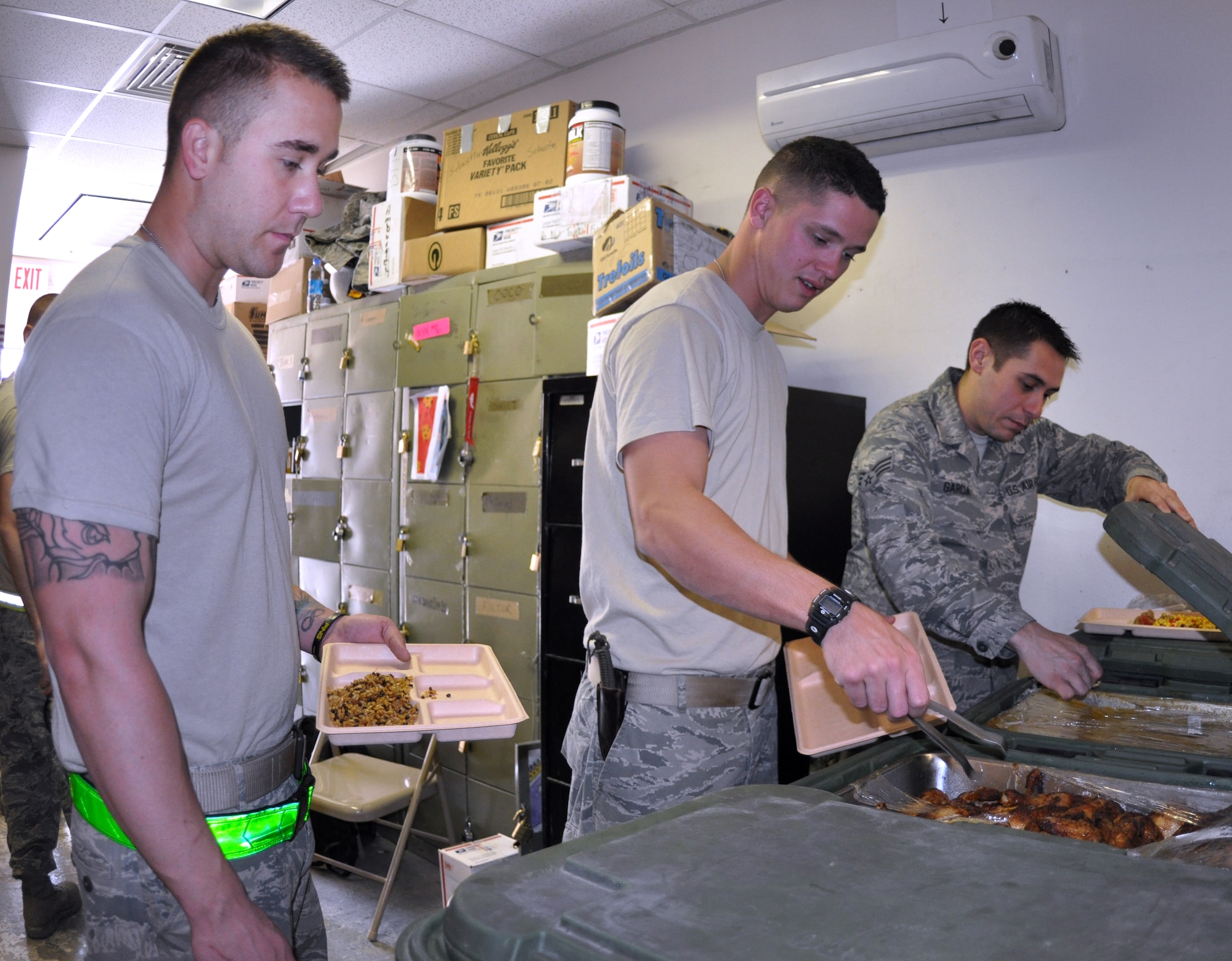Senior Airman Justin Emerson and Senior Airman Micah Hazelip, 60th Aerial Port Squadron aerial porters, get food out of containers for their lunch at the passenger terminal on Bagram Airfield Apr. 12. Due to their demanding work schedule, the porters at the passenger terminal receive their meals from large buffet-style containers, provided to them by the dining facility.
