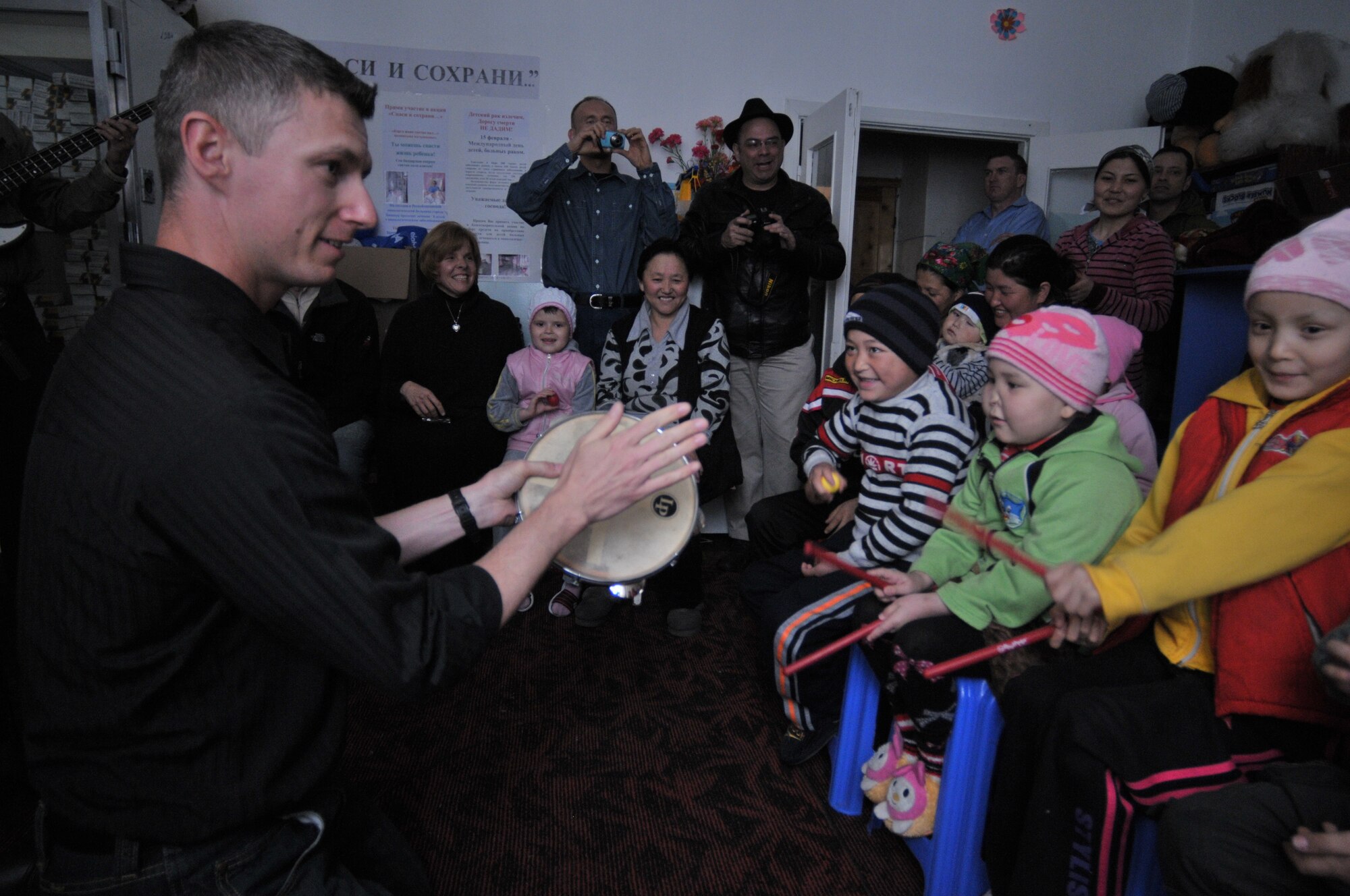 Technical Sgt. Tim Stombaugh, AFCENT Band Wild Blue Country percussionist, teaches Children's Cancer Center patients how to play instruments the band handed out. Each child got to keep an instrument of choice after their performance with Wild Blue Country. (U.S. Air Force photo by Master Sgt. Daniel Nathaniel III)