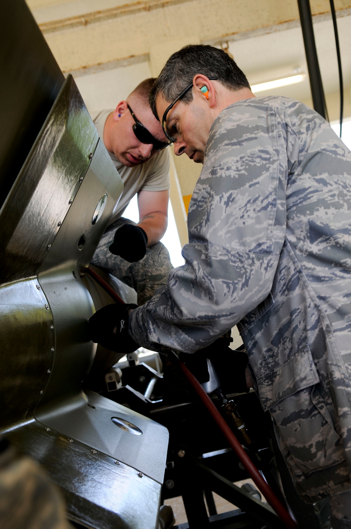 An AMMO troop with the 18th Munitions Squadron, helps Brig. Gen. Kenneth Wilsbach, 18th Wing commander, as he finishes up a GBU-24 (bomb), April 8. Commanders and leaders from the base were given the opportunity to learn common AMMO skills in order to see what a typical AMMO troop goes through during a wing exercise. (U.S. Air Force photo/Senior Airman Sara Csurilla)