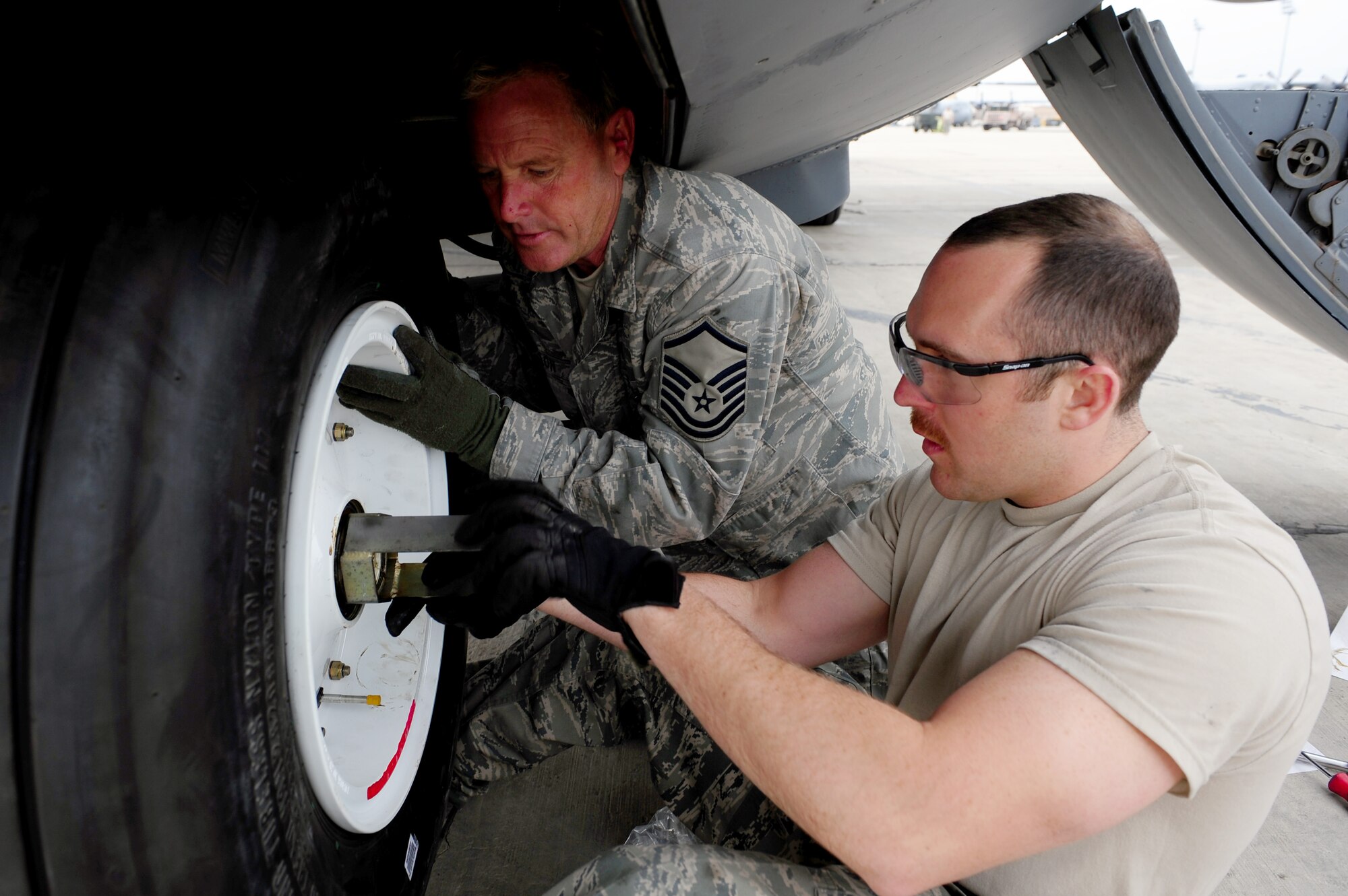 U.S. Air Force Staff Sgt. Justin Greenhow and Master Sgt. Jeff Dillon, 455th Expeditionary Aircraft Maintenance Squadron crew chiefs, secure a new tire to the nose landing gear of a C-130 Hercules aircraft during a tire change procedure at Bagram Airfield, Afghanistan, April 9, 2011. Greenhow and Dillon are deployed from the Delaware Air National Guard’s 166th Aircraft Maintenance Squadron, New Castle, Del., supporting Operation Enduring Freedom. (U.S. Air Force photo/Master Sgt. William Greer)