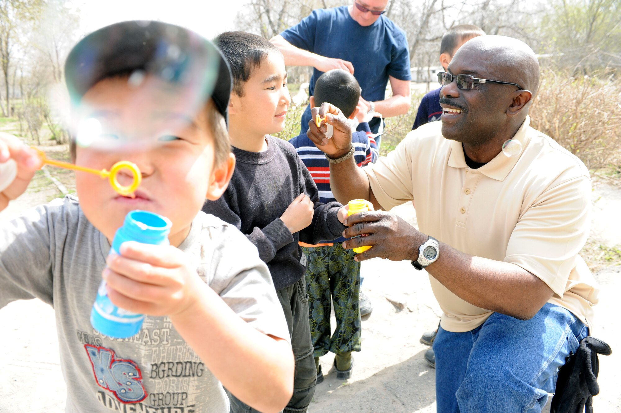NIZNE-CHUISK VILLAGE, Kyrgyzstan - Chaplain (Lt. Col.) Harold Owens, 376th Air Expeditionary Wing, and Master Sgt. Michael Dinneen, 376th AEW chapel, teach children how to make bubbles at the village orphanage here Monday.  Manas Area Benefit Outreach Society reps visited the village to donate blankets and their time for games and laughter with the local youth.  (U.S. Air Force photo/Tech. Sgt. Jerome C. Baysmore) 
