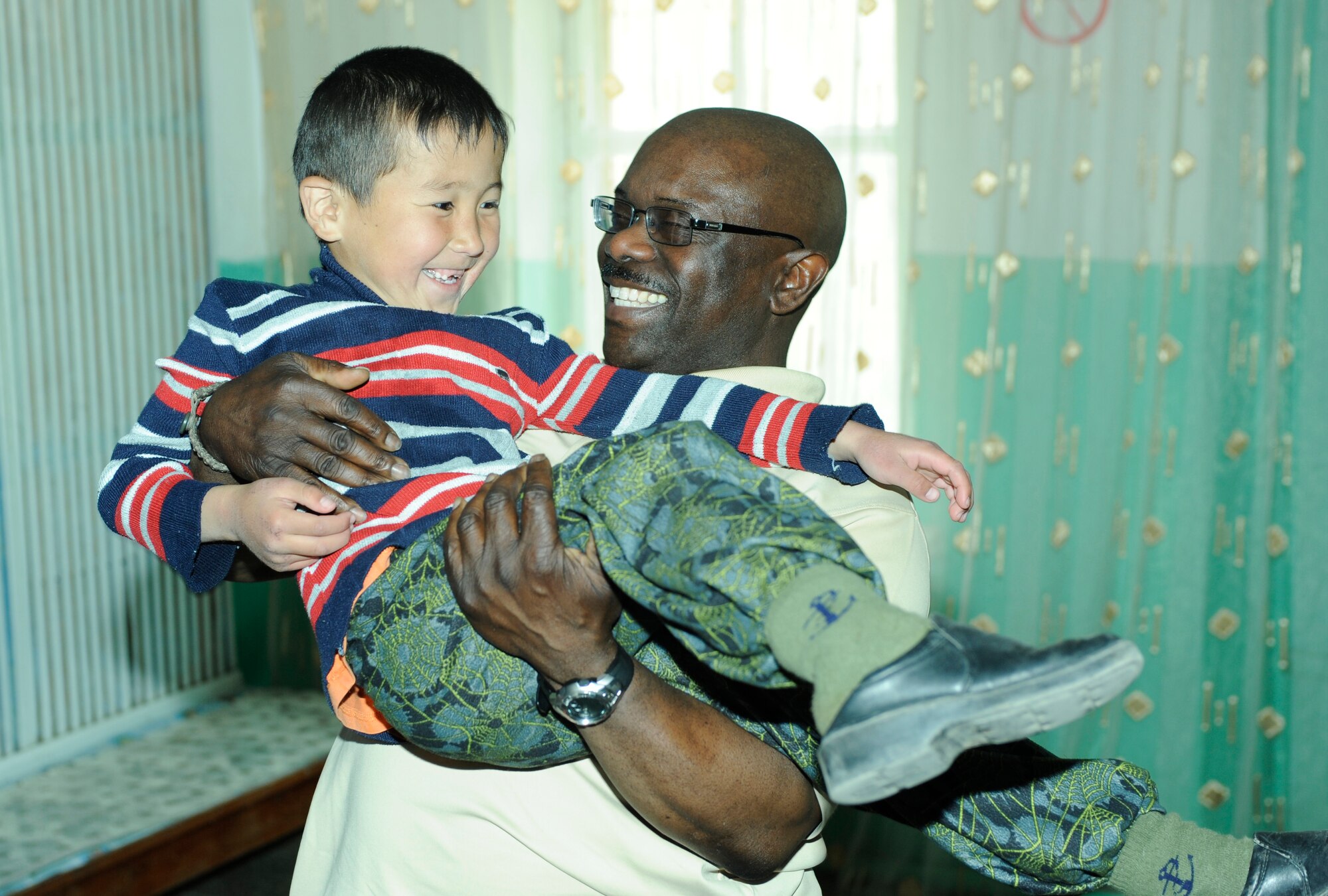 NIZNE-CHUISK VILLAGE, Kyrgyzstan -Chaplain (Lt. Col.) Harold Owens, 376th Air Expeditionary Wing, shares a moment with one of the children at the village orphanage here Monday.  Manas Area Benefit Outreach Society reps visited the village to donate items and their time for games and laughter with the local youth.  (U.S. Air Force photo/Tech. Sgt. Jerome C. Baysmore) 

