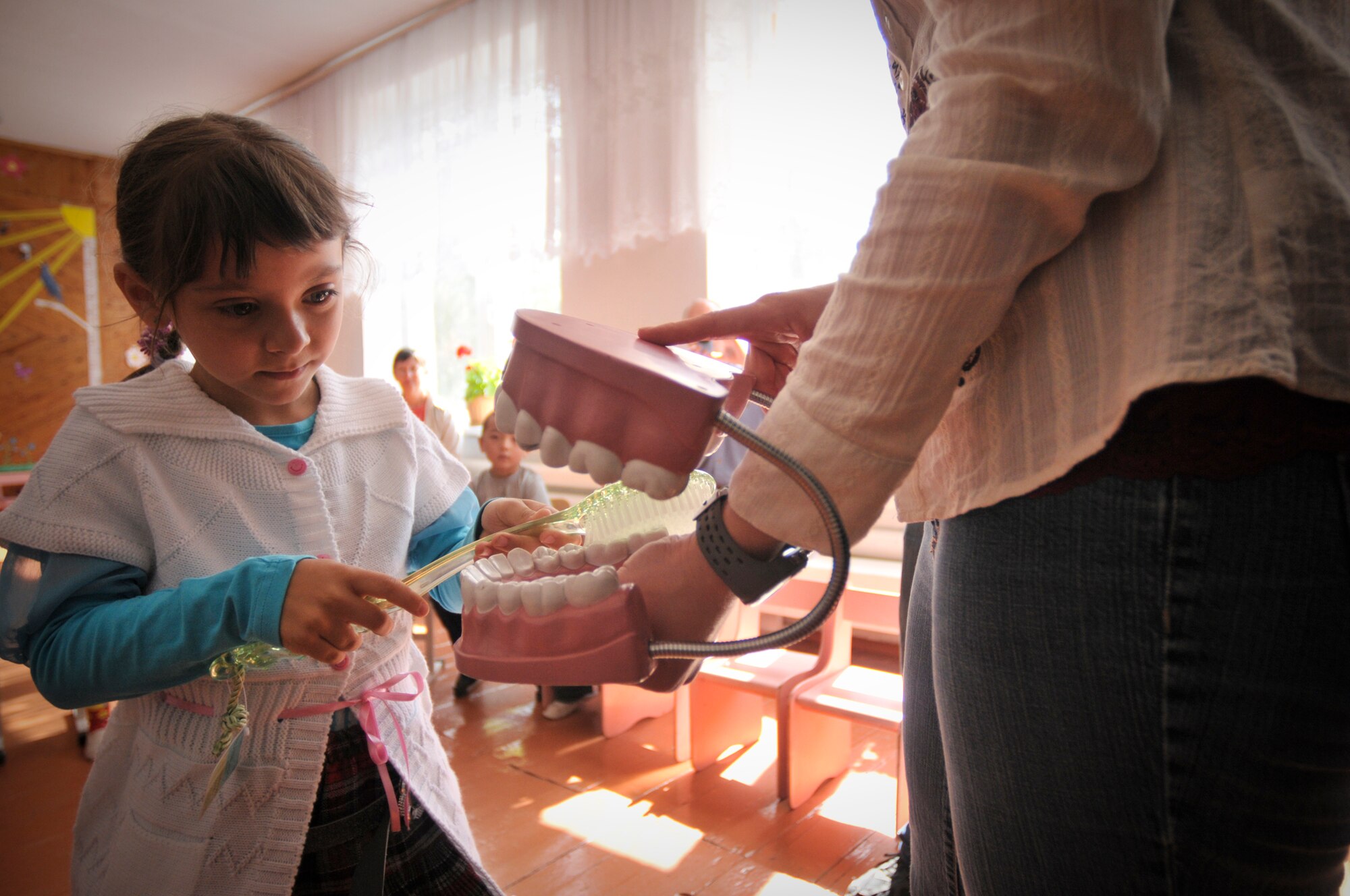 TRANSIT CENTER AT MANAS, Kyrgyzstan  - Members from the Transit Center at Manas meet with children from the Vasilievka school in Vasilievka village  as a part of a Dental outreach mission April 12.  Dental personnel demonstrated the correct way to brush and floss, what kinds of foods are good or bad for teeth and even played a few fun games designed to teach them about teeth. They also donated 90 kits with floss, toothpaste, and tooth brushes, the Civil Air Patrol also donated over 900 dollars and 50 pounds worth of toys and supplies to the school. (U.S. Air Force photo/Staff Sgt. Stacy Moless)


