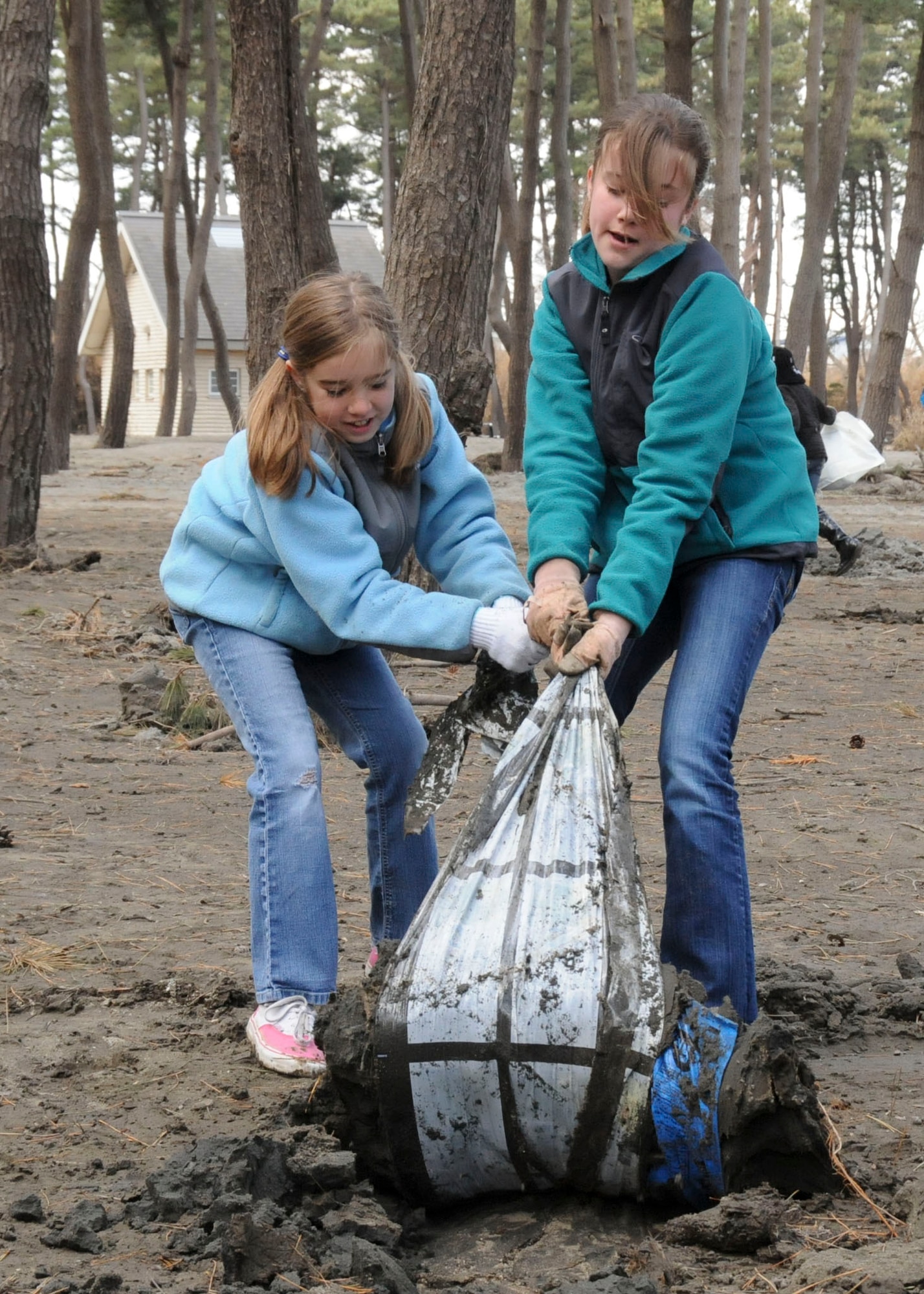 MISAWA AIR BASE, Japan -- Deborah and Emily Jantz, daughters of Lt. Col. Steven Jantz, 35th Operations Support Squadron commander, dig out some buried plastic at a park in Hachinohe, Japan, April 12. Deborah, 10, and Emily, 14, volunteered to clean-up the area along with their parents and younger brother. “We decided it would be a good thing for them to get out here and see what it’s all about,” said their mother, Becky Jantz. (U.S. Air Force photo by Staff Sgt. Rachel Martinez/Released)