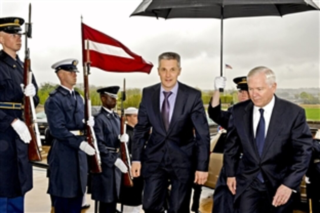 U.S. Defense Secretary Robert M. Gates escorts Latvian Defense Minister Artis Pabriks, left, through an honor cordon under rainy conditions into the Pentagon, April 13, 2011. The defense leaders were to discuss bilateral security issues.