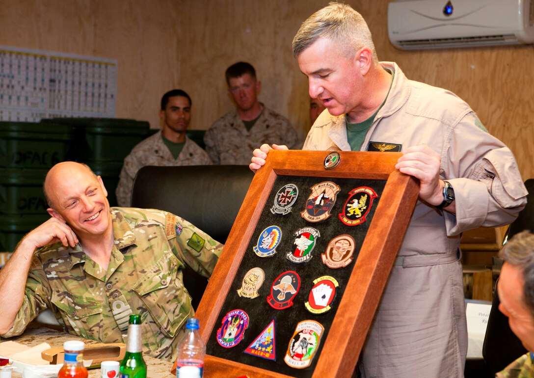 Brig. Gen. Glenn M. Walters presents Royal Navy Capt. Paul Shawcross with a display case featuring a collection of patches representing squadrons with 2nd Marine Aircraft Wing (Forward) during a farewell banquet in honor of Shawcross on Camp Leatherneck, Afghanistan, April 14. Shawcross, the former commander of the United Kingdom’s Joint Aviation Group passed his authority to British Army Air Corps Col. Peter Eadie, April 15. Walters is the commanding general of 2nd MAW (Fwd.)