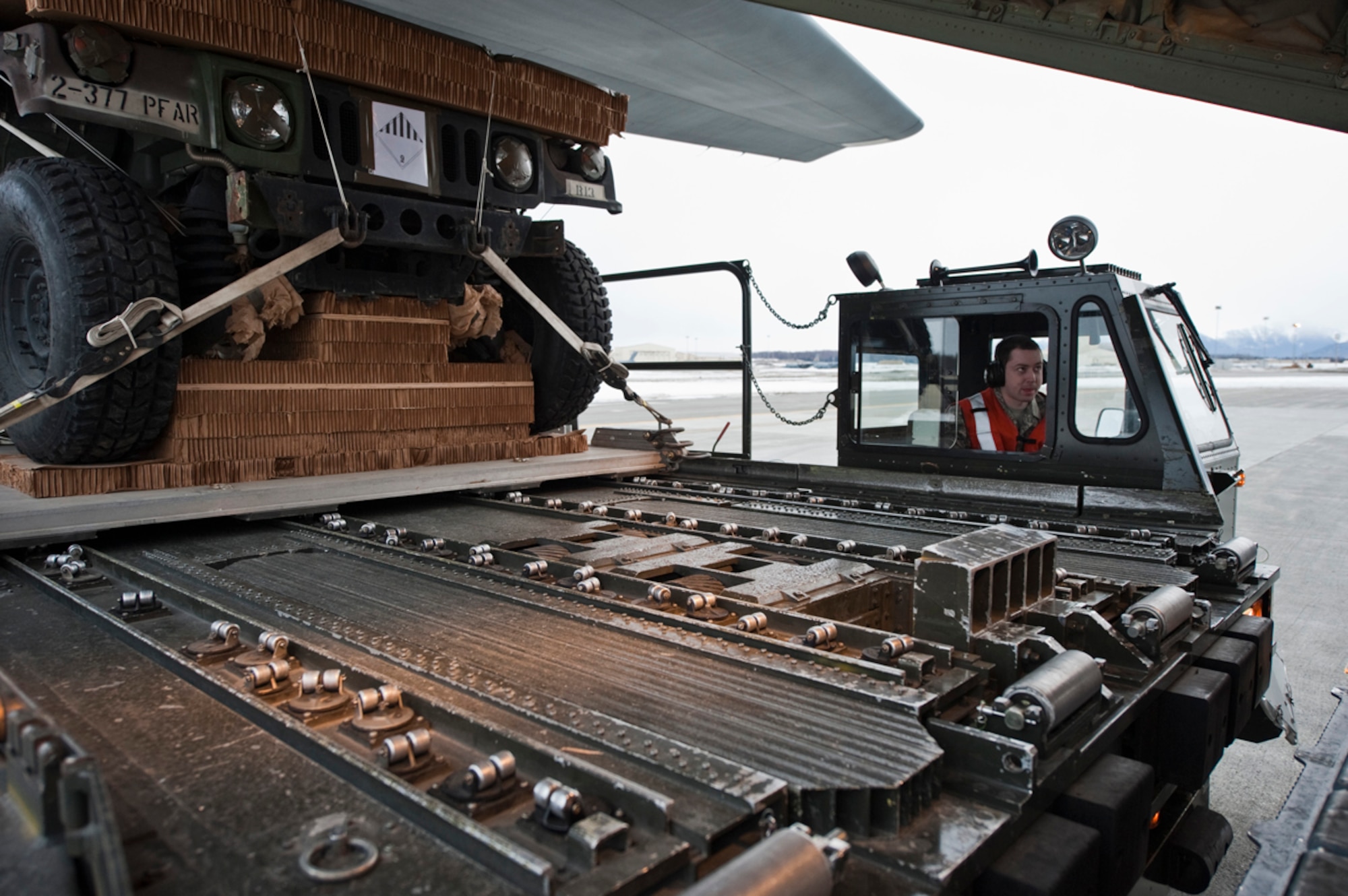 JOINT BASE ELMENDORF-RICHARDSON, Alaska - Senior Airman Brandon Smith, 732nd Air Mobility Squadron, pulls forward while he and other members of the 732nd AMS prepare to load a 32-foot platform consisting of a humvee and howitzer into the back of a C-130 April 4.   The C-130 J Model was from the 19th Airlift Wing, Little Rock Air Force Base, Arkansas. This was in preparation for a heavy drop and personnel drop performed with the 3rd Battalion, 377th Parachute Field Artillery Regiment. (U.S. Air Force photo/Senior Airman Christopher Gross)  