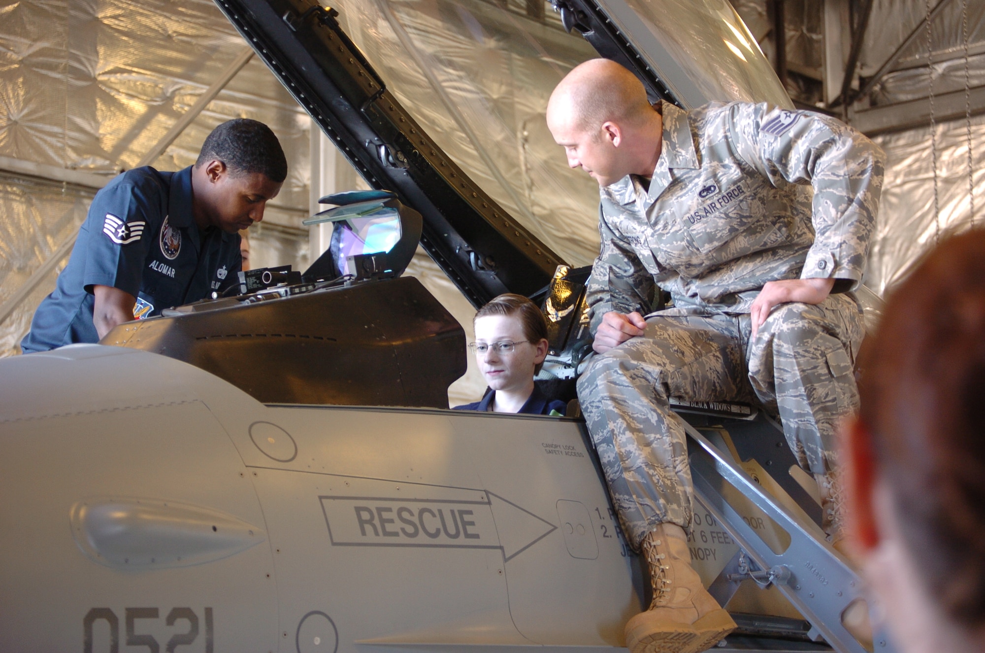 Staff Sgt. Juan Alomar and Staff Sgt. Joshua Armstrong, 388th Aircraft Maintenance Squadron Viper West Demo Team, explain to Tyler Peterson, a student at Snow Horse Elementary School, about some of the controls in the cockpit of the F-16. The students and their families got to sit inside the F-16 and experience what it was like to be a pilot. (U.S. Air Force photo by Airman 1st Class Melissa Dearstone)