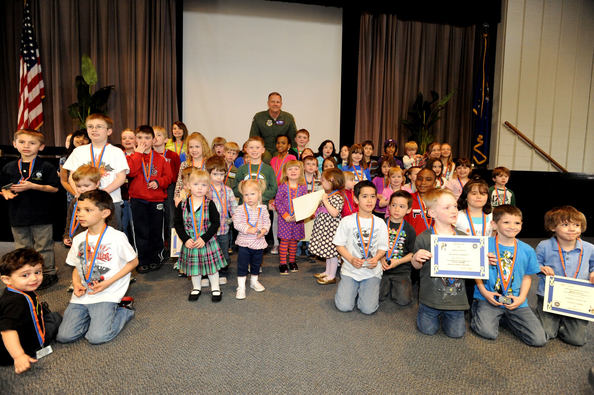 Col. Don Shaffer, 319th Air Base Wing commander, poses with children recognized as '‘Little Heroes’' during the Little Heroes Ceremony Apr. 13 at the base’s Community Activities Center auditorium. The ceremony is held to showcase children who displayed valor during their parent’s deployments, temporary duty, or stationing at remote locations. (U.S. Air Force photo by Airman 1st Class Amber Bennett)