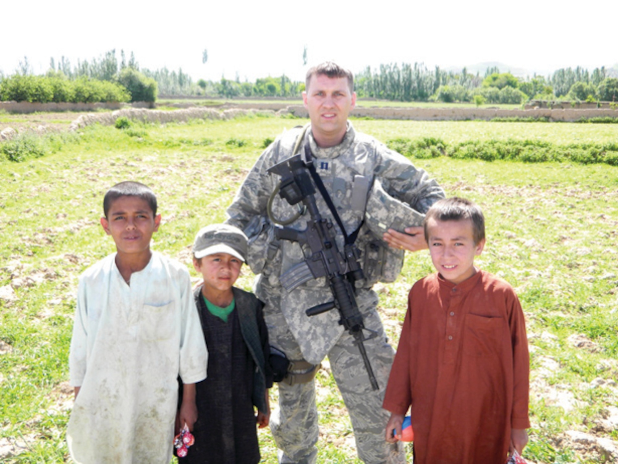 Capt. David Simons, Jr., 452nd Civil Engineer Squadron, March ARB, poses for a photo with Afgan children after handing out candy and toys during his deployment in 2010.  (U.S. Air Force photo/1st Lt. Branden DeLong )
