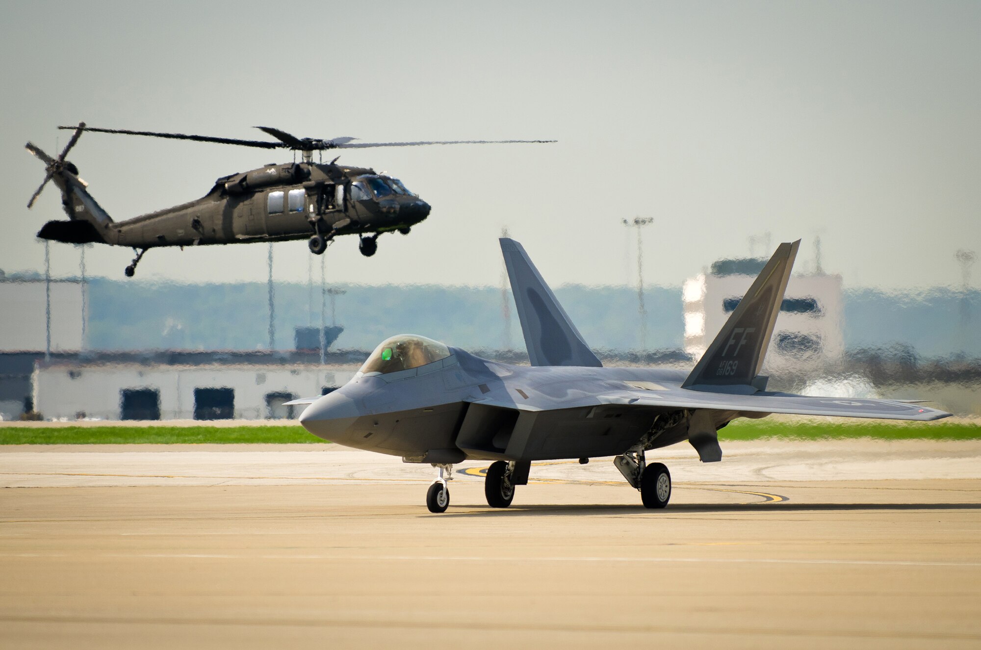 A U.S. Army Blackhawk hovers nearby as a U.S. Air Force F-22 Raptor taxies to its parking spot on the flight line of the Kentucky Air National Guard Base in Louisville, Ky., on April 14, 2011. The Raptor, piloted by Maj. Henry Schantz and assigned to the 1st Fighter Wing at Langley Air Force Base, Va., will appear in the Thunder Over Louisville air show April 16. The annual event is one of the largest single-day air shows in the nation. (U.S. Air Force photo by Maj. Dale Greer)