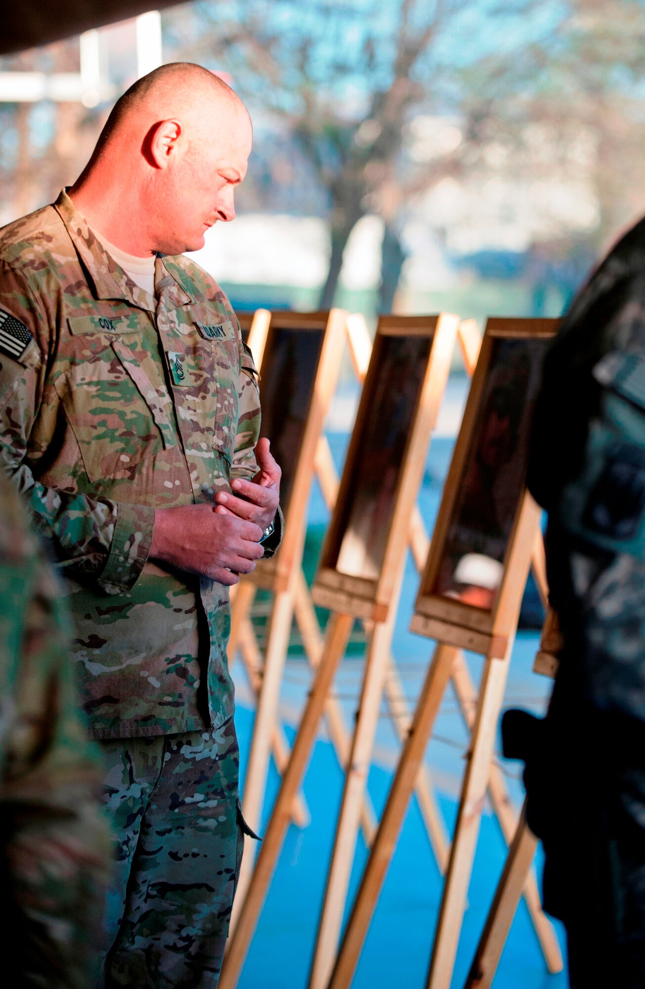BAGRAM AIRFIELD, Afghanistan – A Soldier pauses at a photo of one of 20 fallen servicemembers upon entering the Combined Joint Task Force Paladin 6th Annual Fallen Comrade Memorial here April 5.  Friends and members of CJTF Paladin, an Explosive Ordnance Disposal unit, honored the 20 fallen comrades who had died in combat over the past 12 months.  (Photo by U.S. Army Pfc. Michael Syner, Task Force Falcon PAO)