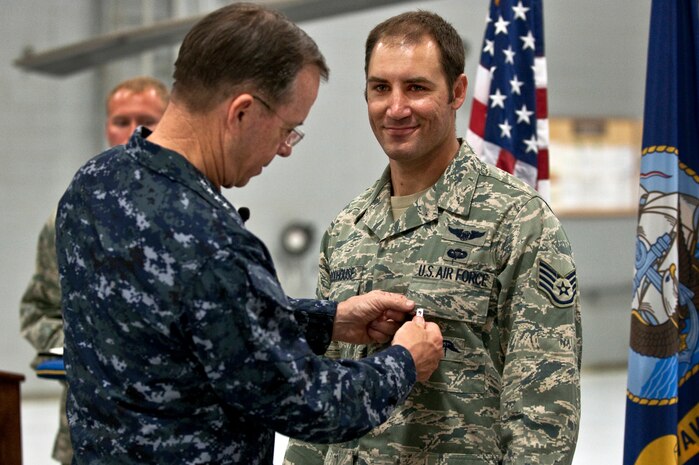 NELLIS AIR FORCE BASE, Nev. -- Chairman of the Joint Chiefs of Staff Navy Adm. Mike Mullen awards a Bronze Star with valor to Staff Sgt. Asher Woodhouse, 58th Rescue Squadron pararescueman, April 13. Sergeant Woodhouse is one of three pararescuemen awarded the Bronze Star for their heroic actions while rescuing American Soldiers last year in Afghanistan. (U.S. Air Force photo by Tech. Sgt. Michael Holzworth)