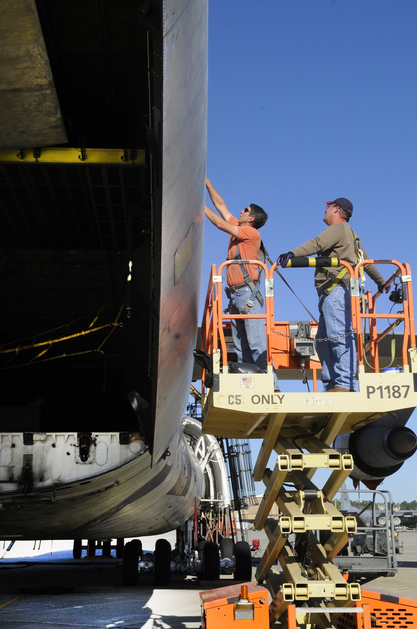 Hubert Watford and Sean Bohannon, C-5 hydraulics, work on the installation of an aft right cargo door. U. S. Air Force photo by Sue Sapp