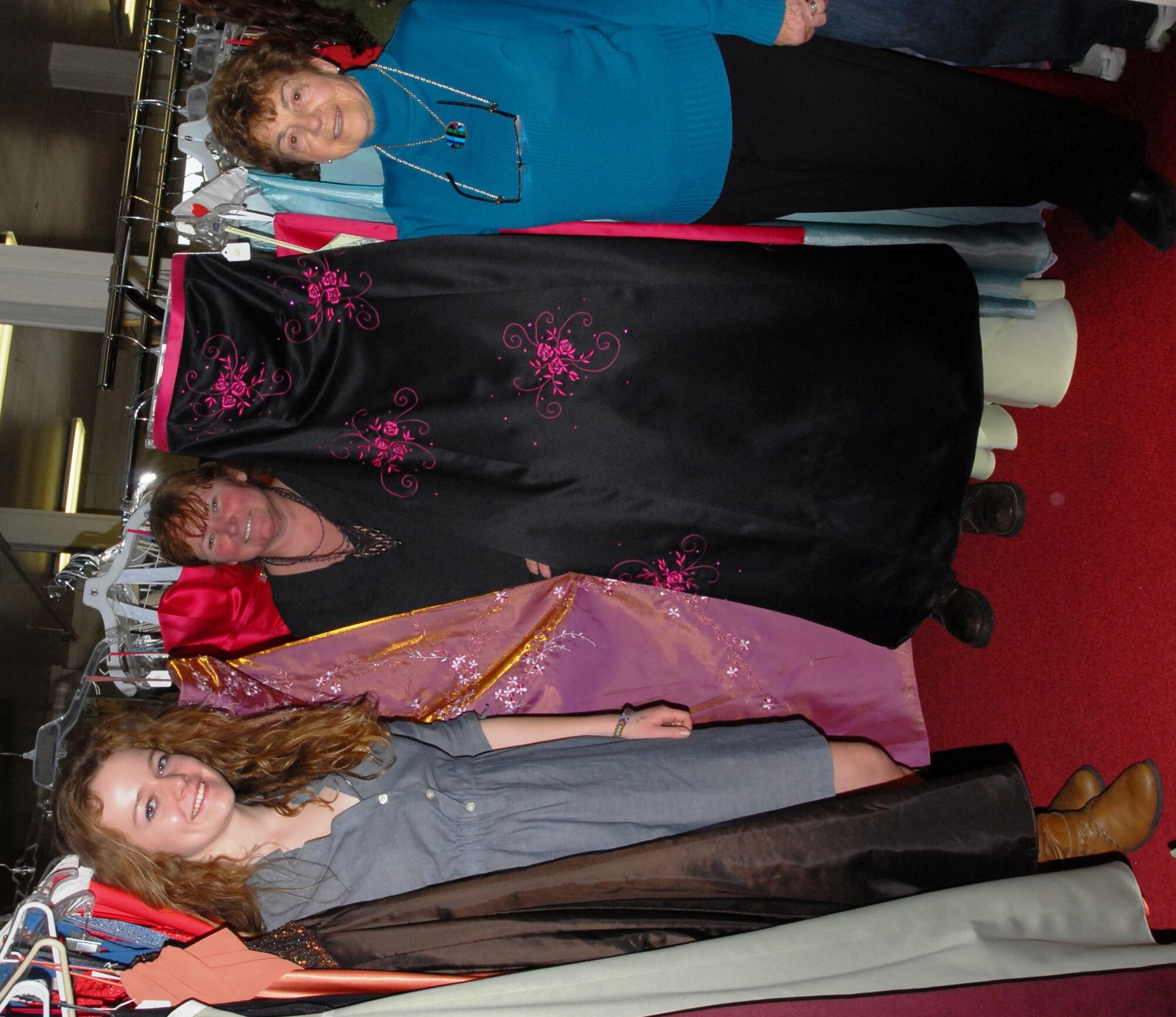 Holly Harrington, local teenager; Suzanne Kinsey, Dix Thrift Store volunteer; and Sylvia Koch, Dix Thrift Store manager, pose with Harrington’s donated dresses, March 31 at the Dix Thrift Store. (Courtesy photo/Released)