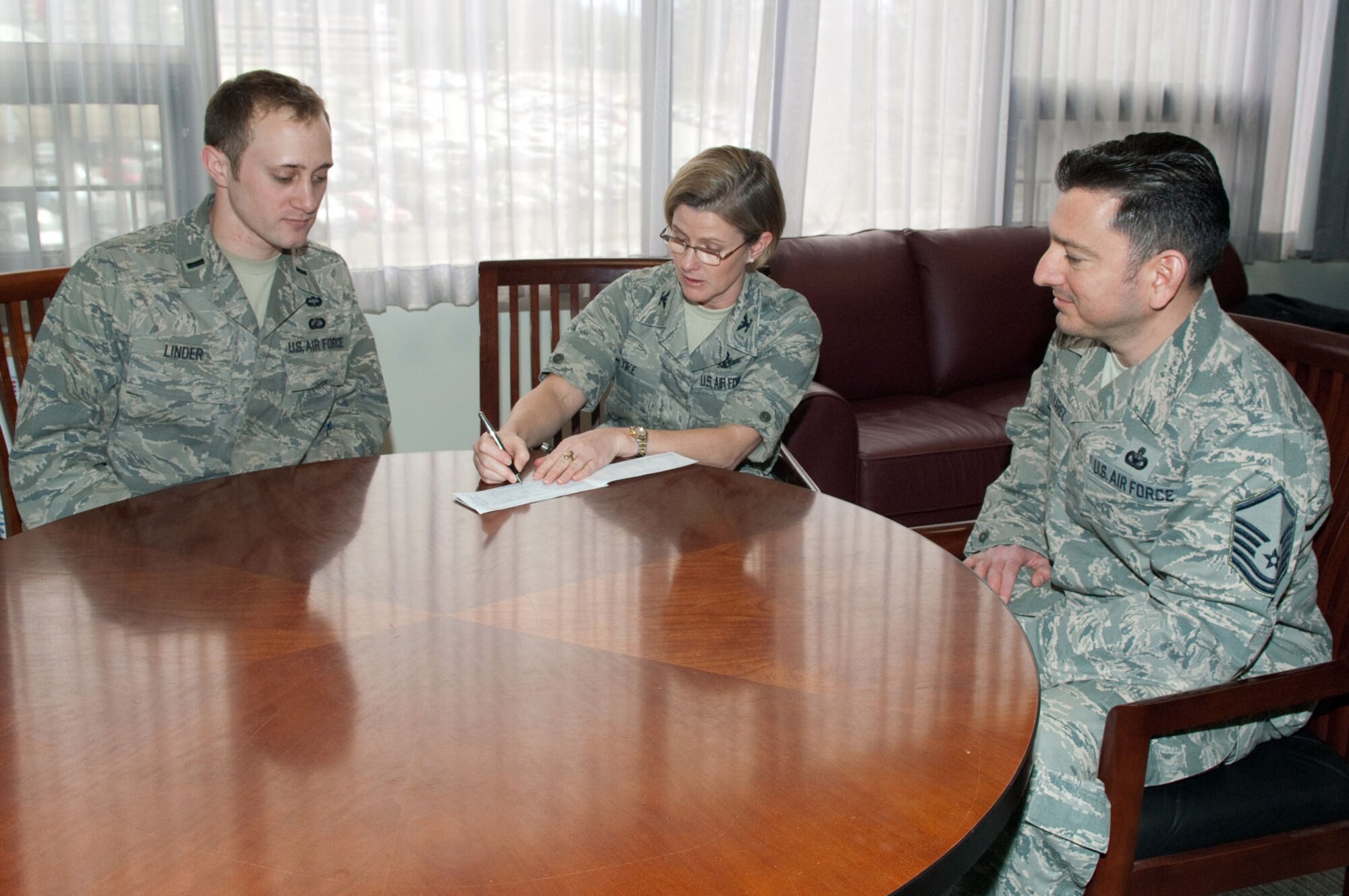 HANSCOM AIR FORCE BASE, Mass. – Col. Stacy L. Yike (center), 66th Air Base Group commander, signs her Air Force Assistance Fund pledge card for Hanscom’s installation project officers 1st Lt. Cameron Linder and Master Sgt. Richard Olivarez (right) April 12. More than $8,000 has been raised and the campaign runs until May 6. (U.S. Air Force photo by Rick Berry) 