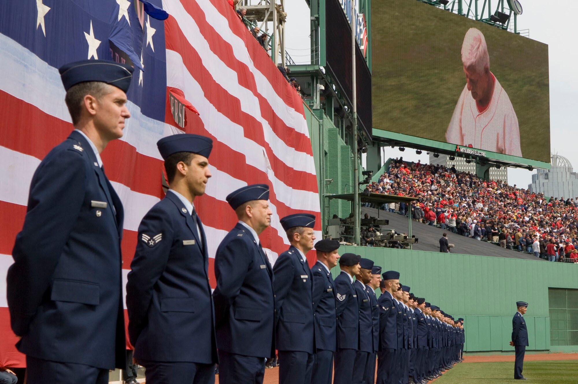BOSTON – Hanscom Airmen, including Col. Mark Spillman (left), Electronic Systems Center vice commander, watch Red Sox legend Carl Yastrzemski prepare to throw the first pitch during opening day festivities at Fenway Park April 8. After the first pitch, the Airmen gathered the American flag from the Green Monster and carried it off the field. (U.S. Air Force photo by Mark Wyatt)
