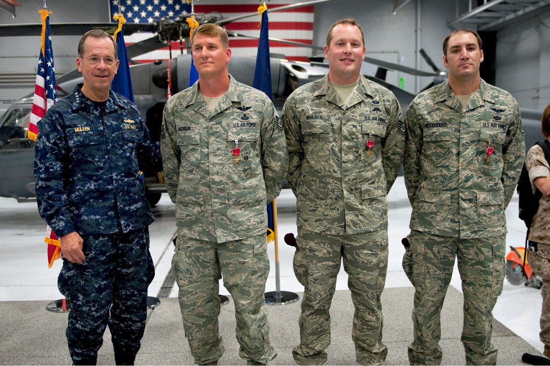 Navy Adm. Mike Mullen, chairman of the Joint Chiefs of Staff, left, poses for photos with Air Force Tech Sgts. Jeffery Hedglin and Ryan Manjuck and Staff Sgt. Asher Woodhouse after the presentation of the Bronze Star during a visit to Nellis Air Force Base, Nev., April 13, 2011.