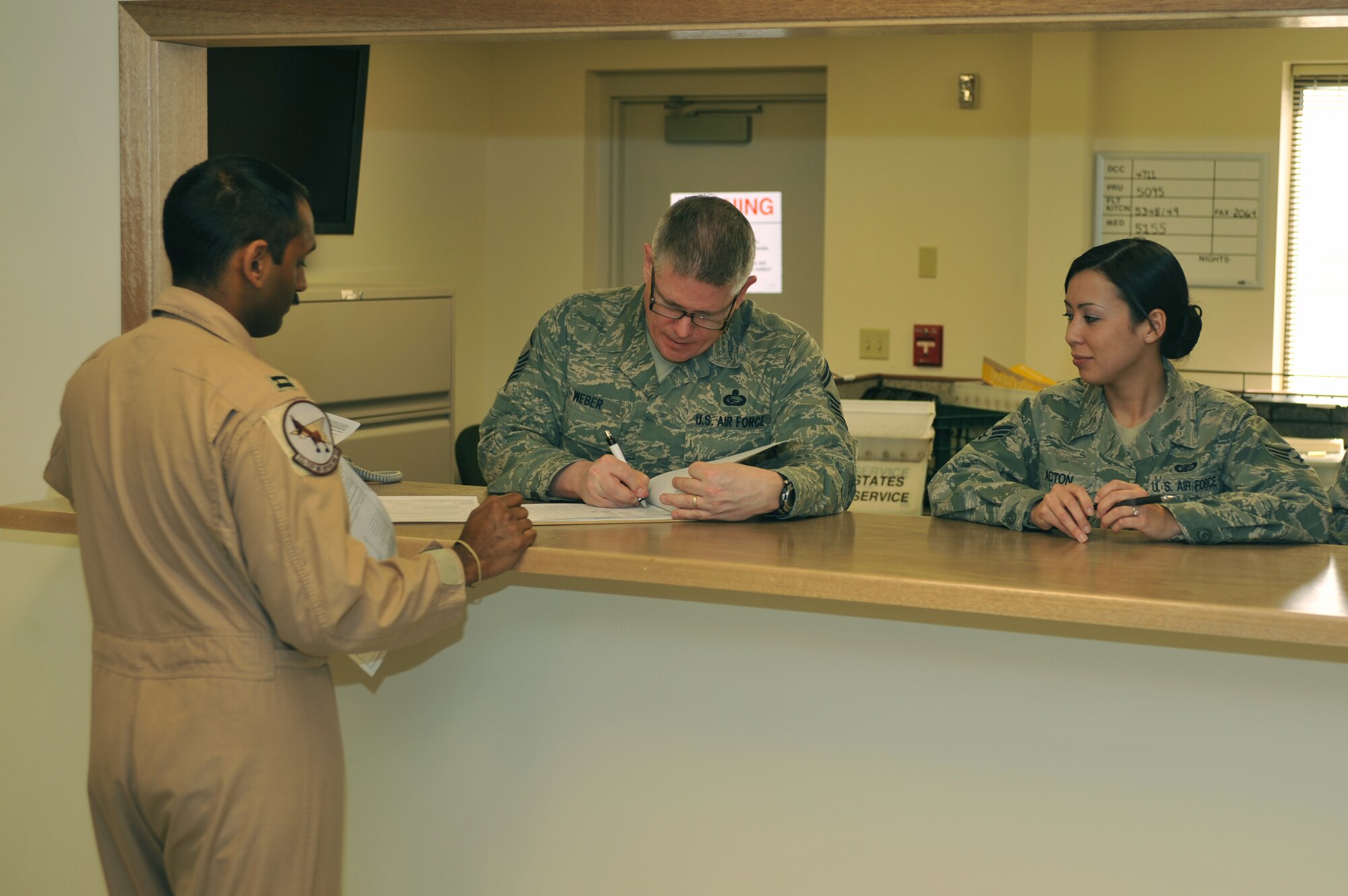 Capt. Calvin D'Silva, 92nd Operations Group pilot, is helped with inprocessing from a deployment by Senior Master Sgt. Scott Weber, 92nd Force Support Squadron personnel readiness superintendent, and Senior Airman Jennifer Acton, 92nd Comptroller Squadron financial technician. In order for Fairchild Air Force Base, Wash., personnel to deploy, the need to be up-to-date 'green' in the Preventative Health Assessment and Individual Medical Readiness program. (U.S. Air Force Photo/Tech. Sgt. Henry Hoegen)