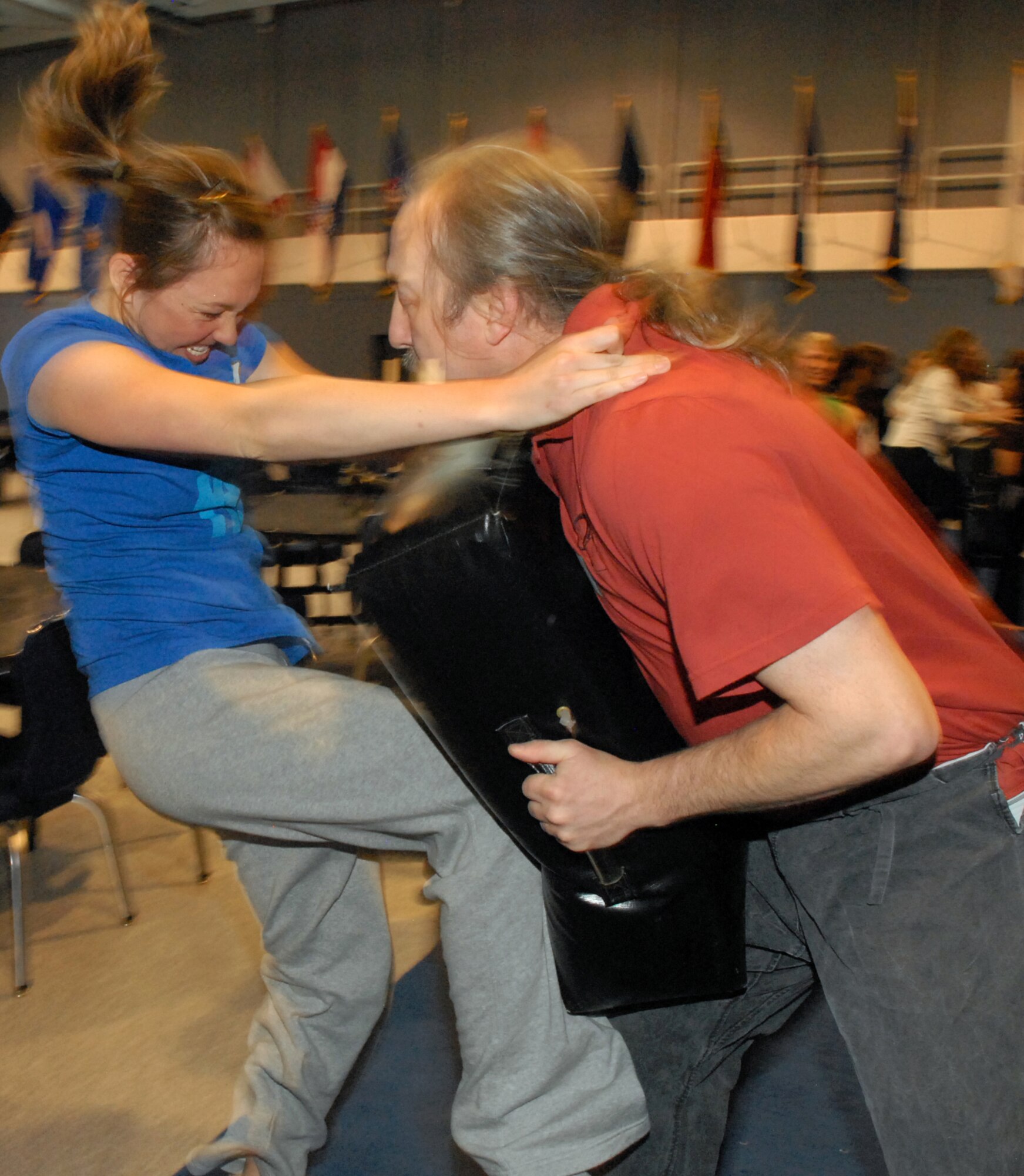 Sarah Eastman throws her weight into the maneuver as she practices “closing the oven door” with instructor Tim Shafer who uses padding for protection during a self-defense course sponsored by the Sexual Assault Prevention and Response program at the Fall Hall Community Center April 7. (U.S. Air Force photo by R.J. Oriez)