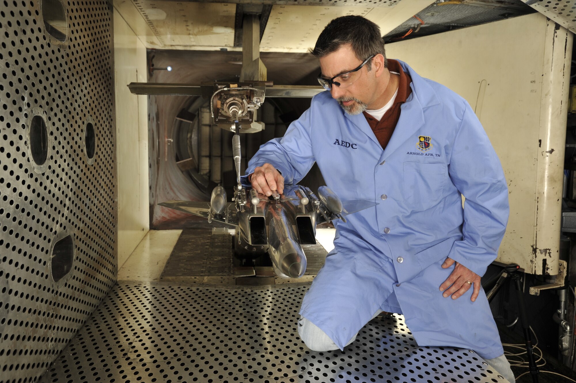 David Anderson, ATA test project engineer, inspects the 1/20-scale models of an F-15E Strike Eagle aircraft and a sting-mounted Small Diameter Bomb (SDB II), during a break in the ongoing store separation test for the new weapon’s development phase trials in the aerodynamic wind tunnel 4T of the Propulsion Wind Tunnel (PWT) facility. The test marks the second time the SDB II has been tested at Arnold. (Photo by Rick Goodfriend)