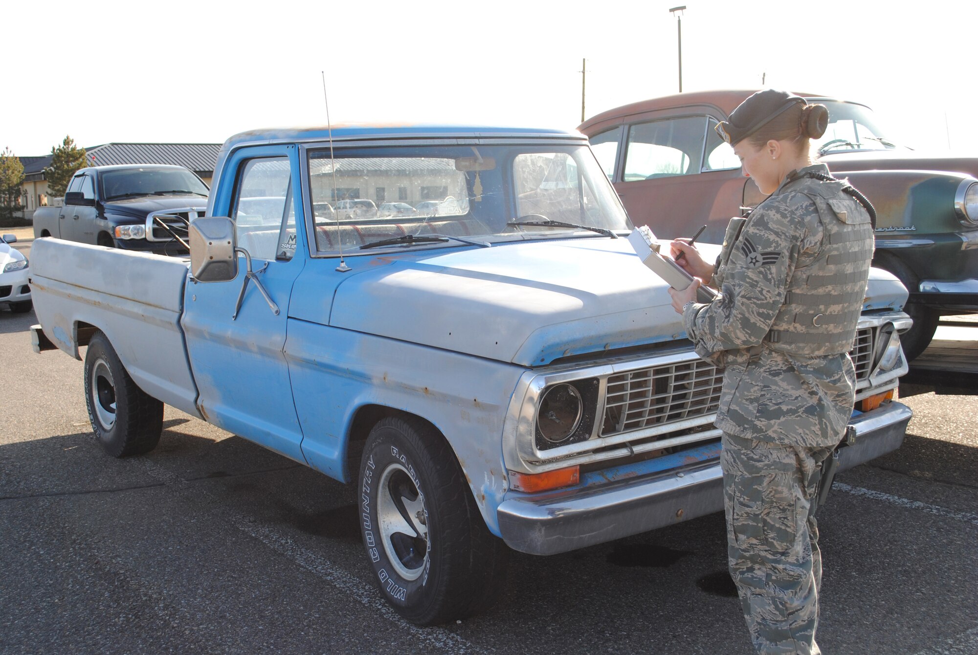 Senior Airman Tonya Saenz, an Air Force Global Strike Command defender from the 341st Security Forces Squadron base defense operations center, writes a citation for a "suspected abandoned vehicle."  Owners of a vehicle receiving this citation have seven days to remove the vehicle before it is impounded.  (U.S. Air Force photo/Airman Cortney Hansen)
