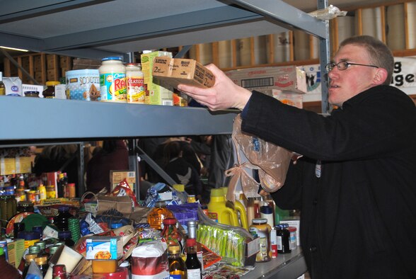 Senior Airman Robert McLain, a 741st Missile Security Forces Squadron security escort team leader, places a donated food item on a shelf for breakables.  Airman McLain was among several members from Malmstrom that volunteered at the food drive. (U.S. Air Force photo/Airman Cortney Hansen)