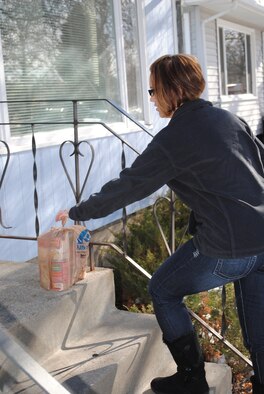 Staff Sgt. Melanie Aylward, 341st Force Support Squadron non-commissioned officer in charge of re-enlistments, picks up a bag of goods on the porch of a Great Falls resident's house.  Sergeant Aylward is a member of the 5/6 Alliance on Malmstrom that helped out with the Scouting for Food event.  (U.S. Air Force photo/Airman Cortney Hansen)