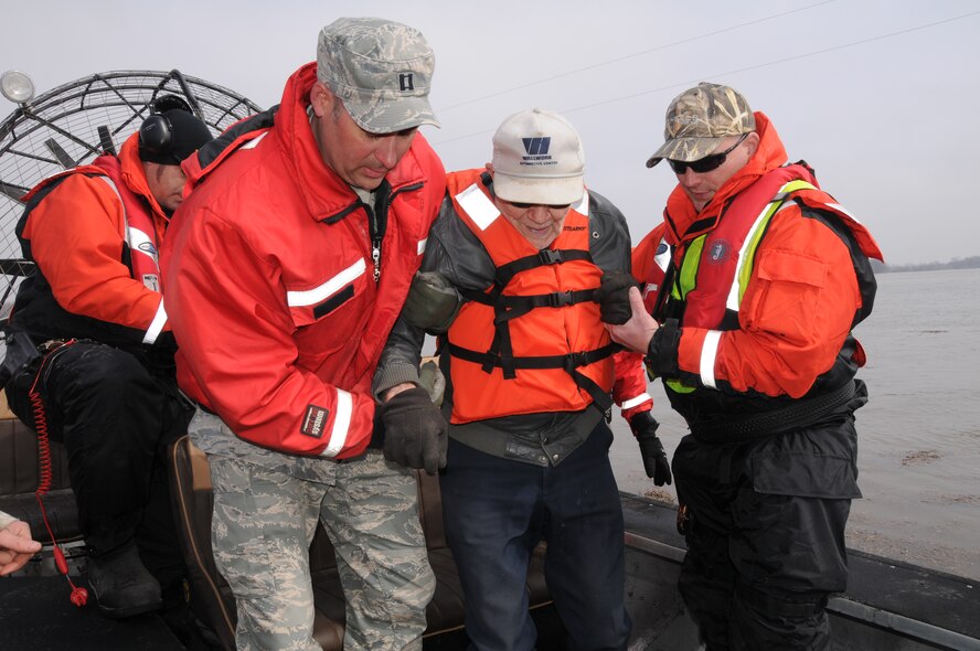 Capt. Grant Larson, of the 119th Maintenance Squadron, left, and Tom Hall, a Cass County Sherriff's deputy, assist 87-year-old Orbert Tenold to his feet April 9, as Tenold is helped out of a Cass County Otter Team airboat near Harwood, N.D.  A joint government agency team is evacuating Tenold from his home, at his request, as floodwater surrounds his residence, making it impossible for him to get out on his own. The team is an example of how agencies are working together to help others during the 2011 Red River Valley flood. As of Saturday April 9, about 480 N.D. Air and
Army Guardsmen are conducting flood operations.
