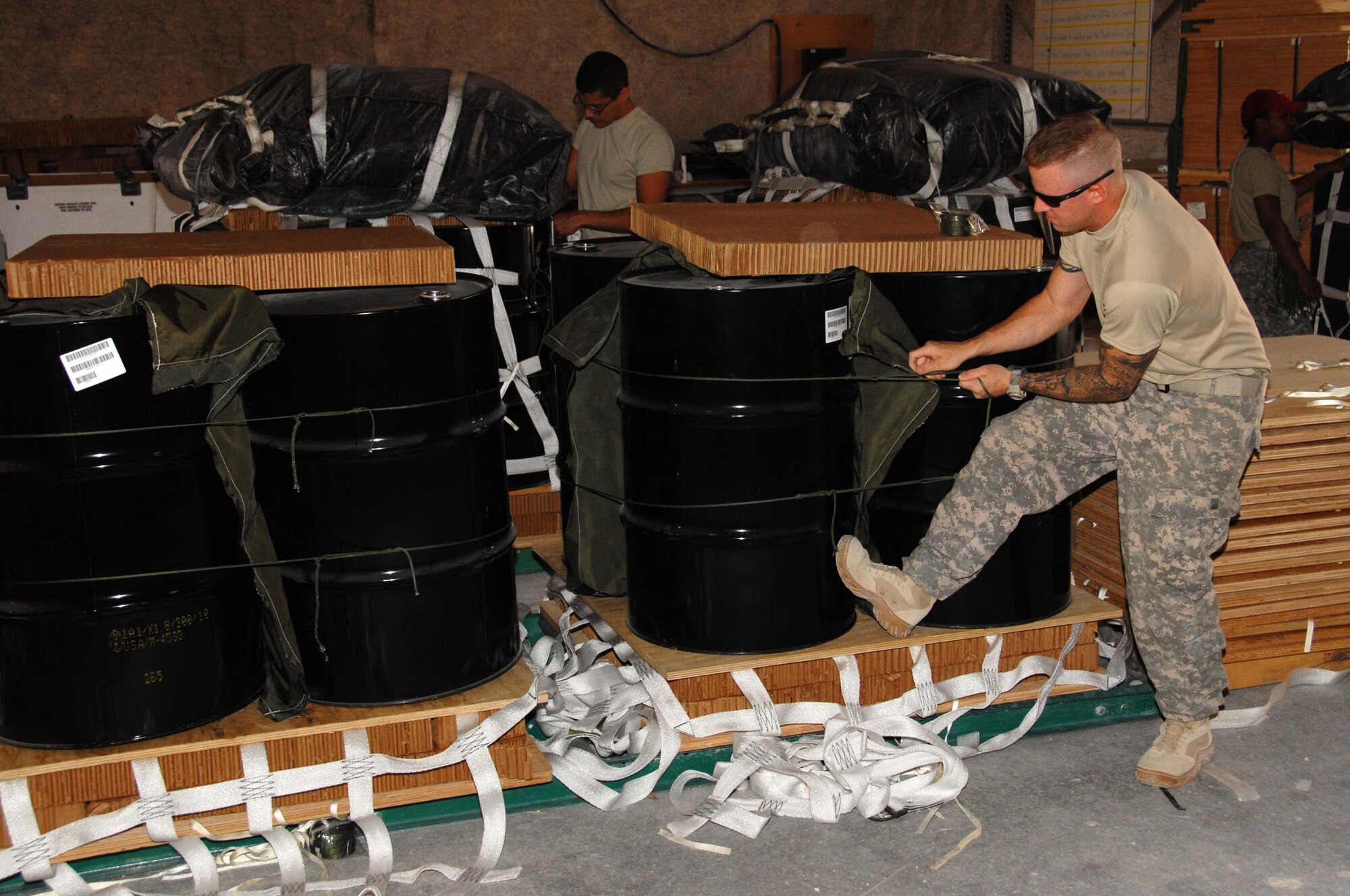 U.S. Army Staff Sgt. Matthew Jones, 824th Quartermaster Company Detachment 10 assembly line NCO, prepares pallets of fuel to be rigged with parachutes on the assembly line. Sergeant Jones is deployed to an undisclosed desert air base in Southwest Asia in support of the airdrop mission to supply remote forward operating bases in the area of responsibility. (U.S. Air Force photo/Staff Sgt. Anthony Graham)