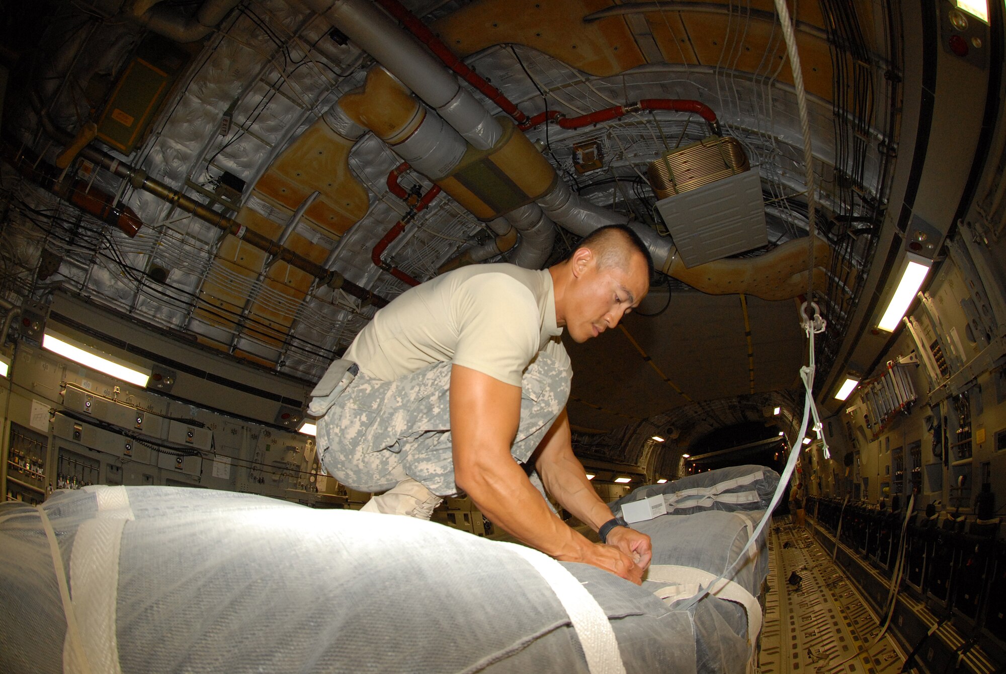 U.S. Army Staff Sgt. Sisamone Sirivong, assigned to the 824th Quartermaster Company Detachment 10 “Airborne Riggers,” finishes rigging the parachutes on a C-17 before the air drop mission.  (U.S. Air Force photo/Staff Sgt. Anthony Graham)