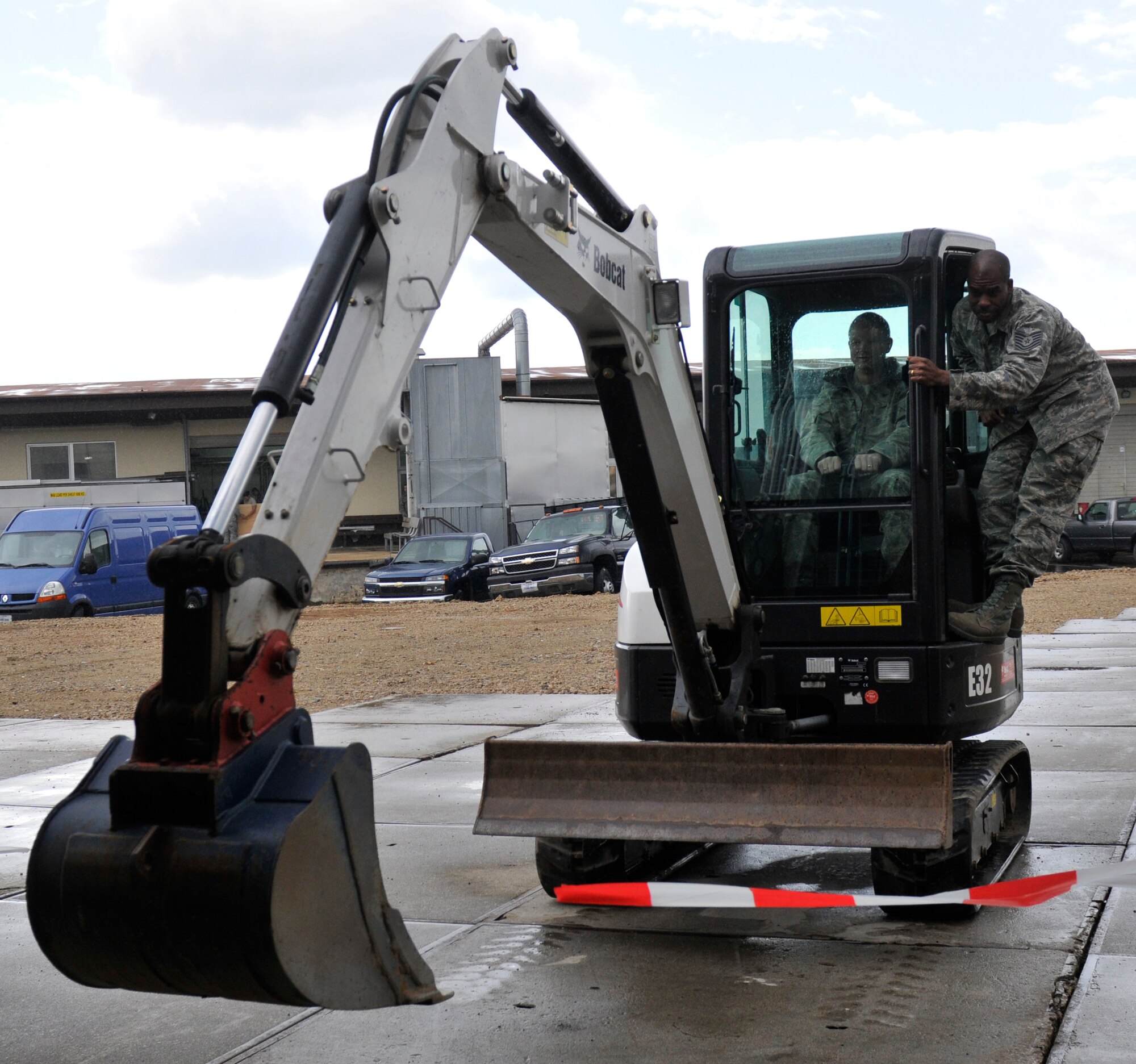 SPANGDAHLEM AIR BASE, Germany- Col. Christopher Weggeman, 52nd Fighter Wing commander, and Tech Sgt. Eric Wilson, 52nd Civil Engineer Squadron equipment operator, cut a ribbon using a Bobcat excavator here April 12. The ribbon-cutting ceremony took place after two warehouses were constructed by the 435th Construction and Training Squadron from Ramstein Air Base, Germany. The warehouses were built to consolidate materials and manpower in preparation for the Bitburg Annex closure. (U.S. Air Force photo/Airman 1st Class Brittney Frees)