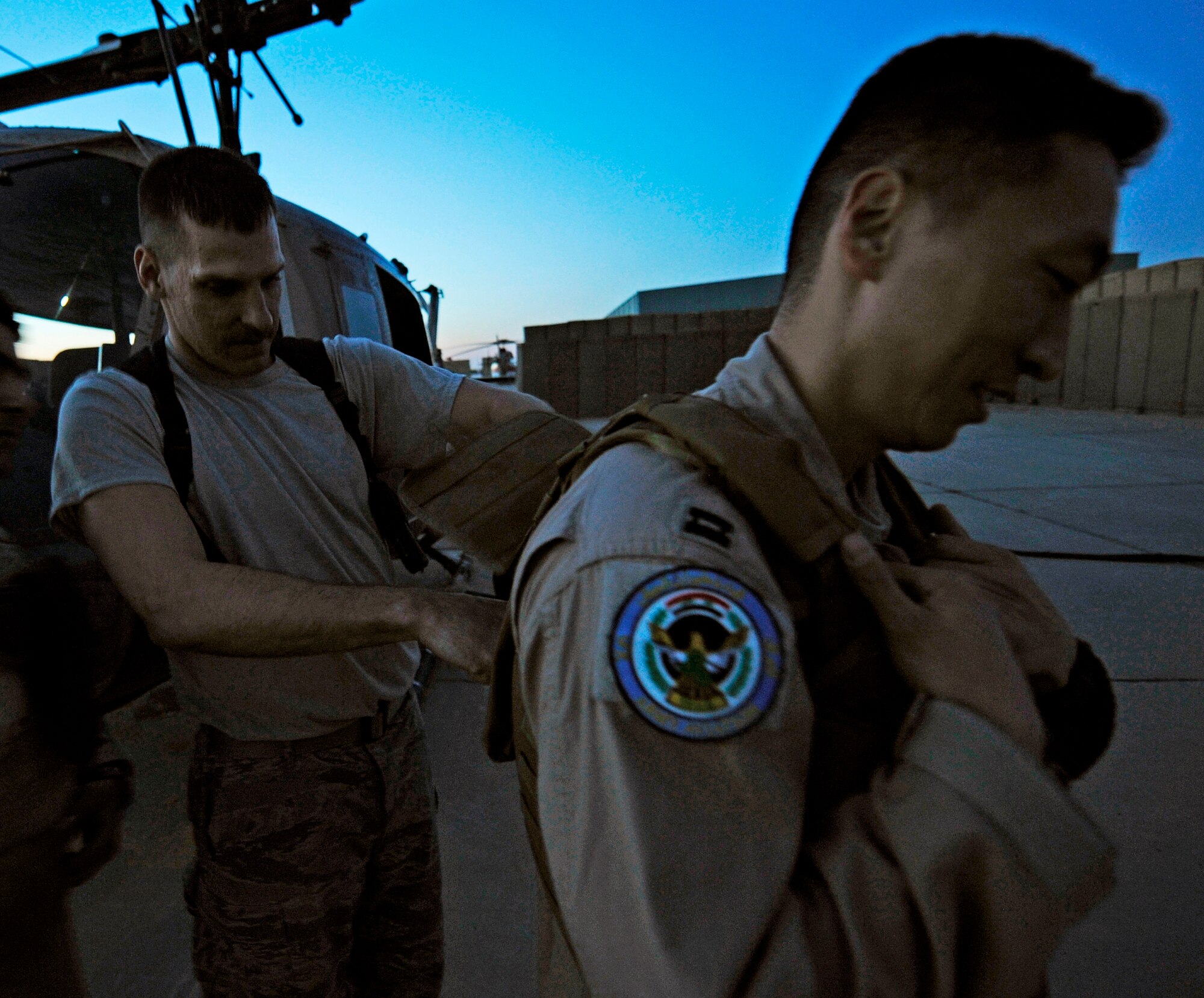 CAMP TAJI, Iraq -- Tech. Sgt. Chuck Hall, left, 721st Air Expeditionary Advisory Squadron chief air operations advisor deployed from Charleston, S.C., helps Capt. Jun Oh, a 721st AEAS instructor pilot deployed from Yokota Air Base, Japan, gear up for his final UH-1 Huey mission with Iraqi co-pilots March 15. Sergeant Hall is from Springfield, Ohio, and Captain Oh calls Seoul, Republic of Korea, his hometown. (U.S. Air Force/Tech. Sgt. Jason Lake)