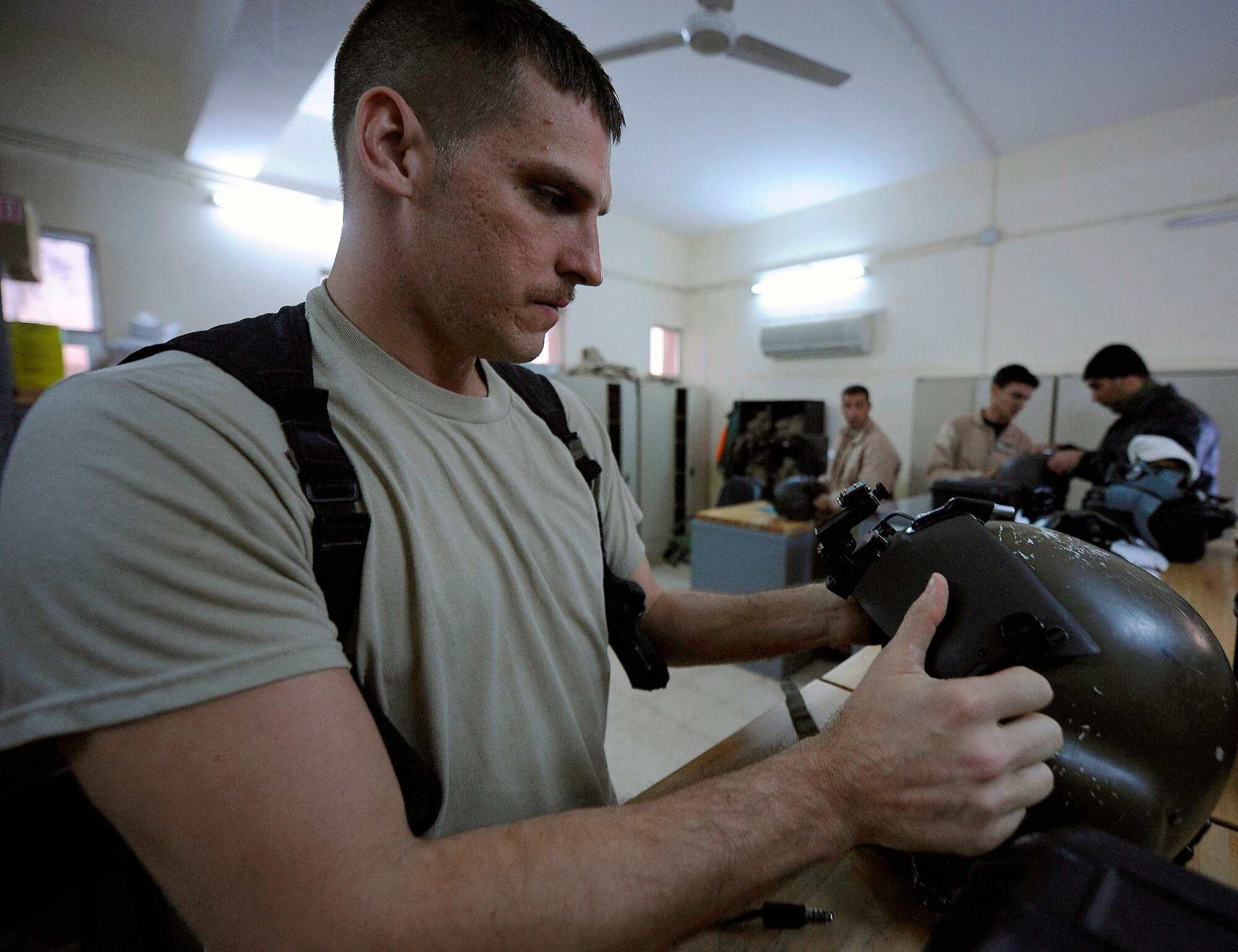 CAMP TAJI, Iraq -- Tech. Sgt. Chuck Hall, 721st Air Expeditionary Advisory Squadron chief air operations advisor, inspects helmets for Iraqi Army Aviation Command Squadron 20 pilots prior to the final UH-1 Huey airborne mission with U.S. instructors on-board. Sergeant Hall is deployed from Joint Base Charleston, S.C., and calls Springfield, Ohio his hometown. (U.S. Air Force/Tech. Sgt. Jason Lake)