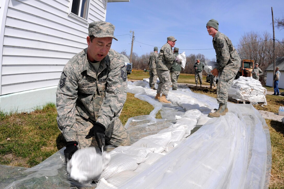 Air Force Master Sgt. David Bush places sandbags into position as he and members of a North Dakota National Guard quick response force team build a sandbag levee around a rural farmstead home near Kindred, N.D., April 14, 2011. Bush is assigned to the 119th Civil Engineer Squadron.