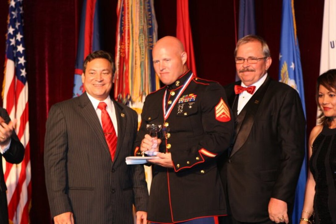Sgt Justin Dues, from Marine Forces Pacific (Fwd), receives his award from Governor Eddie Calvo.  Dues was awarded the Marine of the Year award at the 6th annual Guam United Services Organizations (USO) gala, which was held at the Hyatt Regency Hotel, Guam, April 16th. The event honored members from each military branch for their voluntary service.