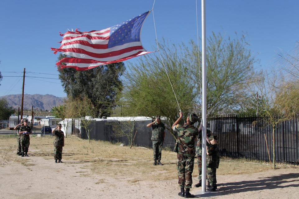 A tattered flag is lowered at the Atlas Self Storage facility in Twentynine Palms by members of the Combat Center’s Young Marines Program during a colors ceremony to replace a worn and faded flag with a new one April 16, 2011.::r::::n::