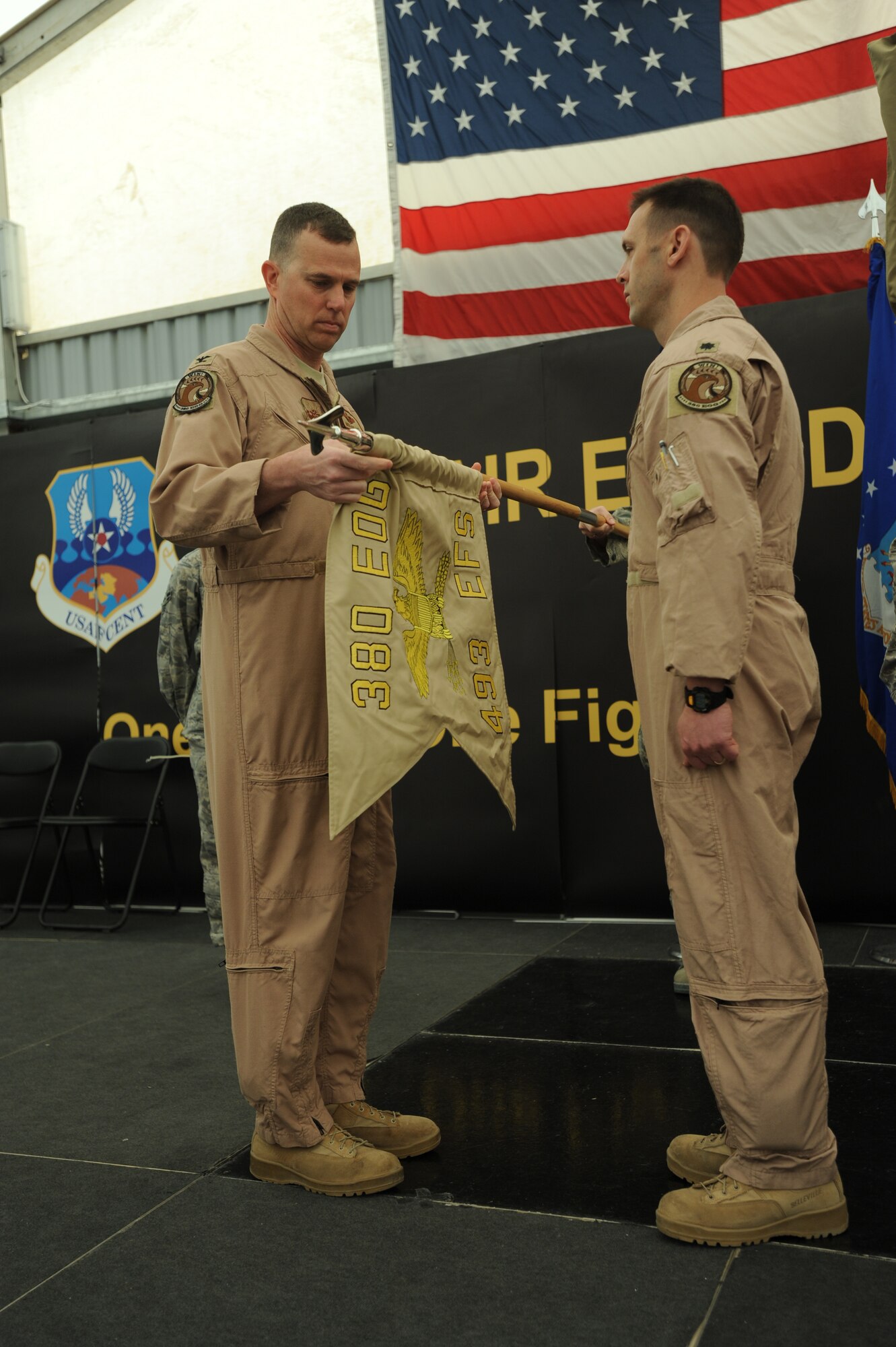 Col. Gregory Guillot, 380th Expeditionary Operations Group commander, unfurls the 493rd Expeditionary Fighter Squadron guidon flag while Lt. Col. Skip Pribyl, new 493rd EFS commander, awaits the activation orders for the ceremony April 11, 2011. Colonel Pribyl is deployed from the 493rd Fighter Squadron, Royal Air Force Lakenheath, United Kingdom. (U.S. Air Force photo by Senior Airman Maynelinne De La Cruz)