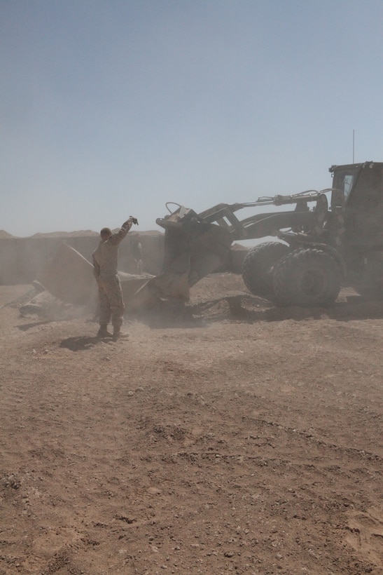 Lance Cpl. Jonathan J. Limrick, a combat engineer with Marine Wing Support Squadron 272, directs a bulldozer clearing ground debris to expand a forward arming refueling point at Combat Outpost Ouellette in Afghanistan’s Helmand province, April 17. The forward arming refueling point was recently constructed at the combat outpost to enable 2nd Marine Aircraft Wing (Forward) to better support Marines and other coalition troops operating near Sangin, Afghanistan “We are constructing barriers, buffing up the base perimeter and building fuel bladders,” said Limrick. “This is all part of making Ouellette bigger to support the ground troops better.”