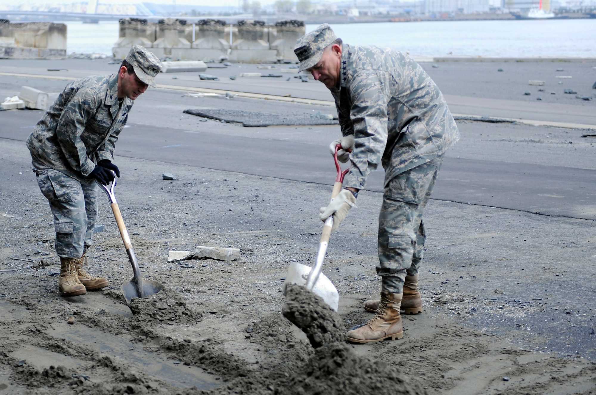MISAWA AIR BASE, Japan -- Col. Michael Rothstein, 35th Fighter Wing commander, left, and Gen. Gary North, Pacific Air Forces commander, shovel sand at the Hachinohe Port April 16. The Misawa Helps program is a volunteer organization dedicated to assisting communities that have been affected by the earthquake that occurred on March 11. (U.S. Air Force photo by Staff Sgt. Marie Brown\Released)
