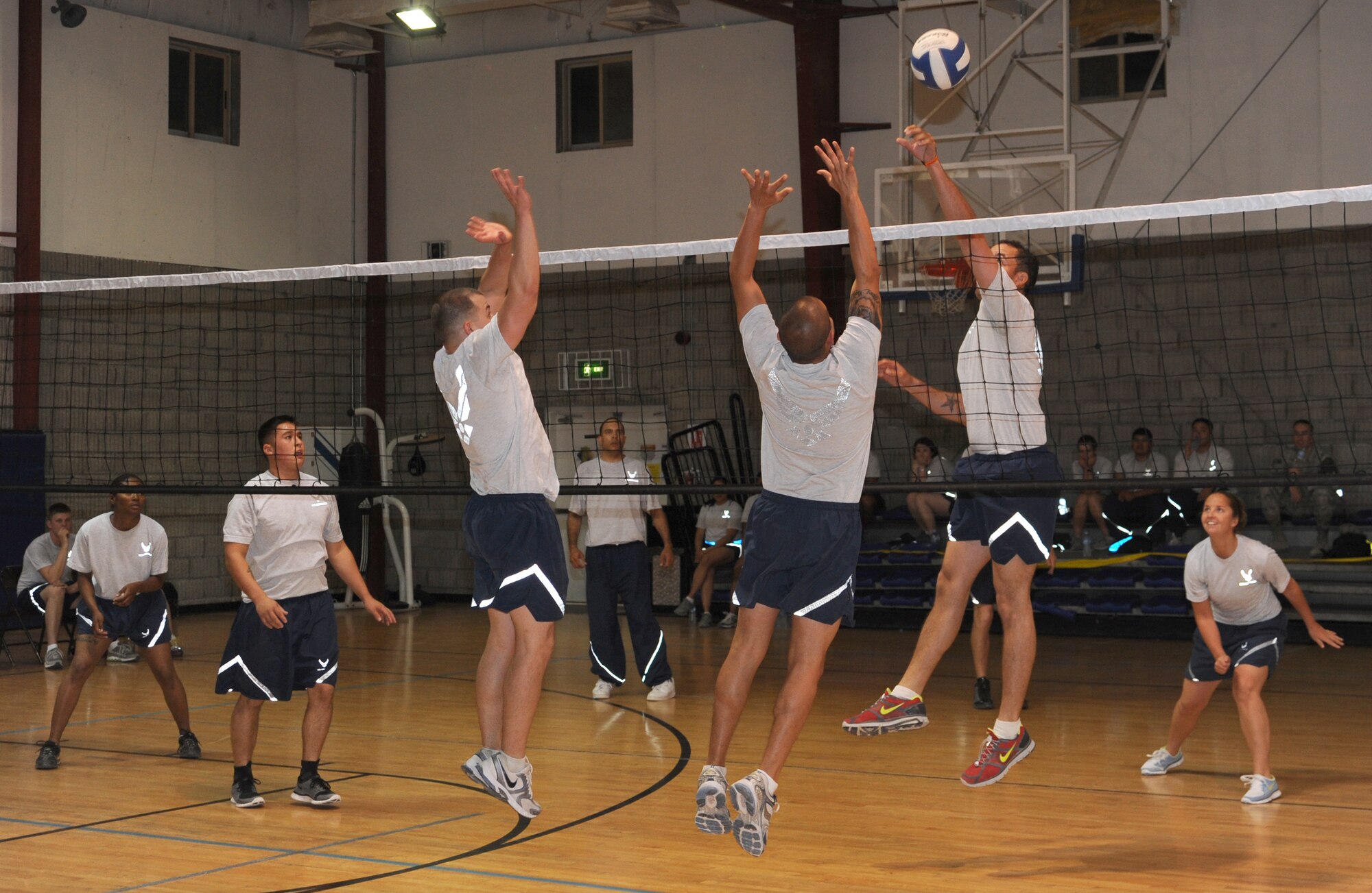 Senior Airman Brandon Parks, 379th Expeditionary Civil Engineer Squadron Third Country National escort, jumps to return the ball as Senior Airmen Chris Riley and Jacob Banuelos, 379 ECES firefighters, attempt to block the shot during a volleyball game April 13.  (U.S. Air Force photo/Staff Sgt. Liliana Moreno)                                   