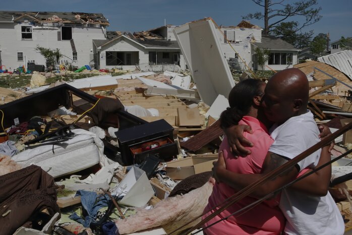 Petty Officer 2nd Class Fredrick Lacy, head operation’s petty officer for 2nd Dental Battalion, 2nd Marine Logistics Group, embraces his wife after surveying the remains of their house aboard the Tarawa Terrace housing community, Marine Corps Base Camp Lejeune, April 15. The Lacys’ house was one of the hardest hit residences from the tornado that ripped through the TT area shortly after 8 p.m. Saturday night, one of approximately 12 that were completely demolished.