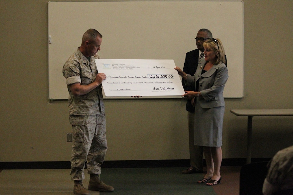Brigadier Gen. H. Stacy Clardy, III, the Combat Center’s commanding general, accepts a check from Marine Corps Community Services Director Katherine Catlin during a ceremony to recognize the Combat Center’s volunteers April 18, 2011. The check, in the amount of $2.16 million, represents the value of more than 92,000 labor hours contributed by Combat Center volunteers during 2010.::r::::n::