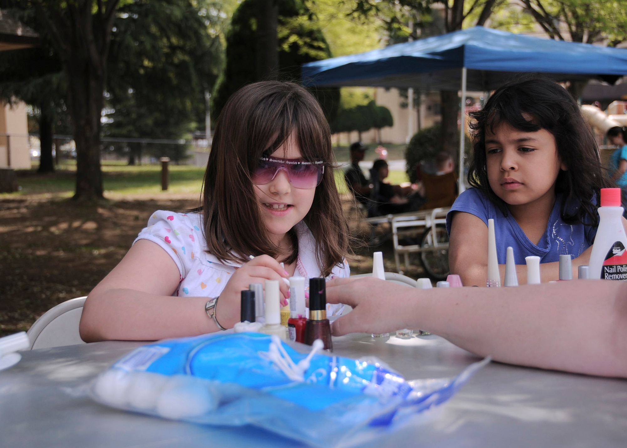 YOKOTA AIR BASE, Japan -- Melody Morey, (left), age 7, paints a customer's nails with assistance from her friend Alma Verastegui, age 8, during Tomodachi Stock 2011 here April 16. Throughout the event, the two girls were able to raise more than $500 that will benefit the earthquake and tsunami relief efforts. (U.S. Air Force photo/Senior Airman Andrea Salazar)
