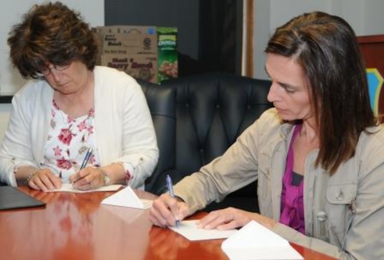 (Left) Anita Eichhorn, wife of Air Force Operational Test and Evaluation Center Commander Maj. Gen. David Eichhorn, joins Denise Eck, wife of AFOTEC Vice Commander Col. James Eck, in writing notes of encouragement and thanks to deployed team members that were included in quarterly care packages.