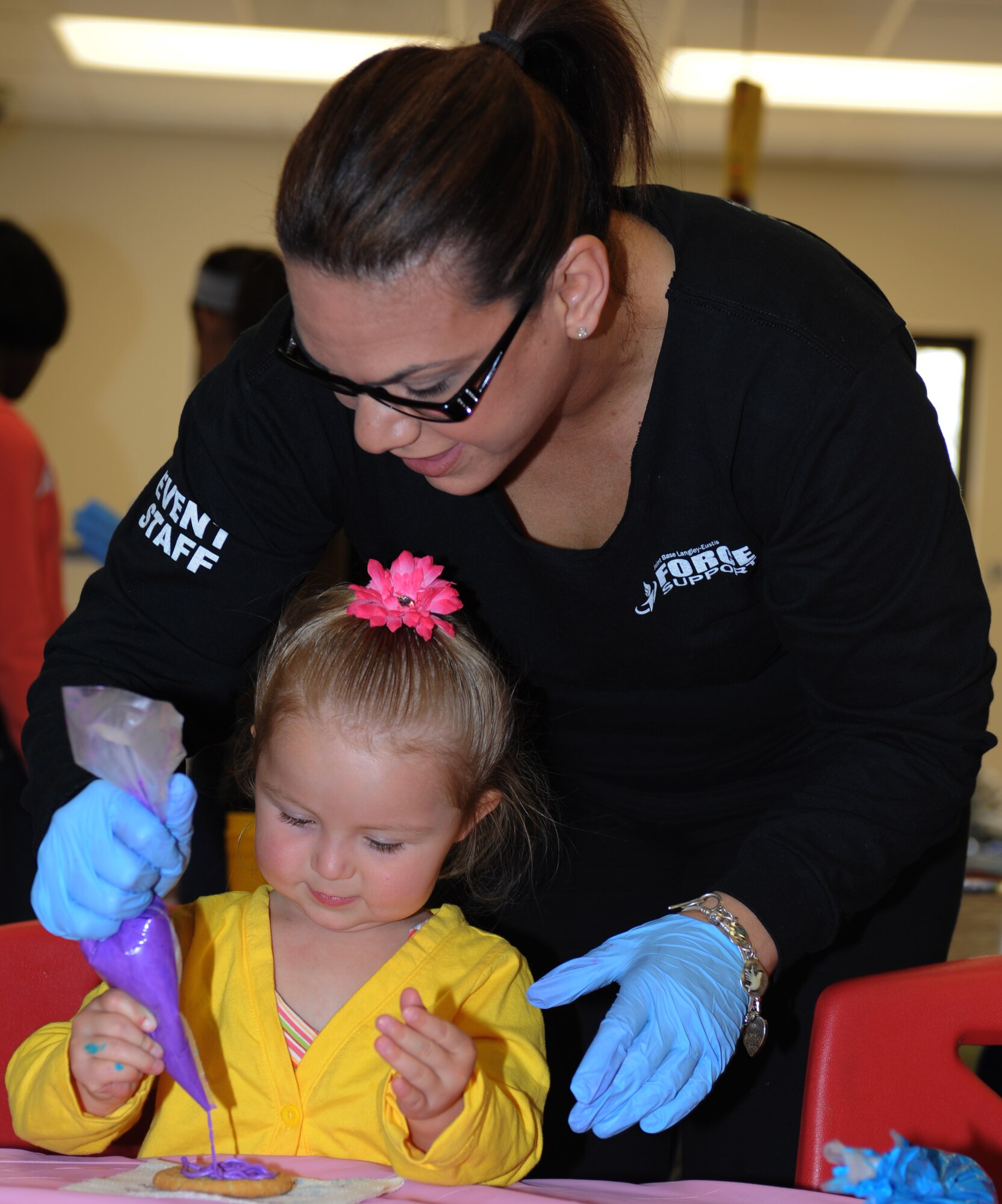 Angela Wainwright, Airman and Family Readiness Center program assistant, helps Bailey Comer, two year old daughter of Staff Sgt Sari Comer, 633d Comptroller Squadron, decorate sugar cookies during the Month of the Military Child Extravaganza at Langley Air Force Base, Va., April 16, 2011. Children enjoyed Easter egg hunts, face painting, arts and craft and many other activities at the Bethel Manor Youth Center to celebrate. (U.S. Air Force photo/Airman 1st Class Teresa Zimmerman/Released)