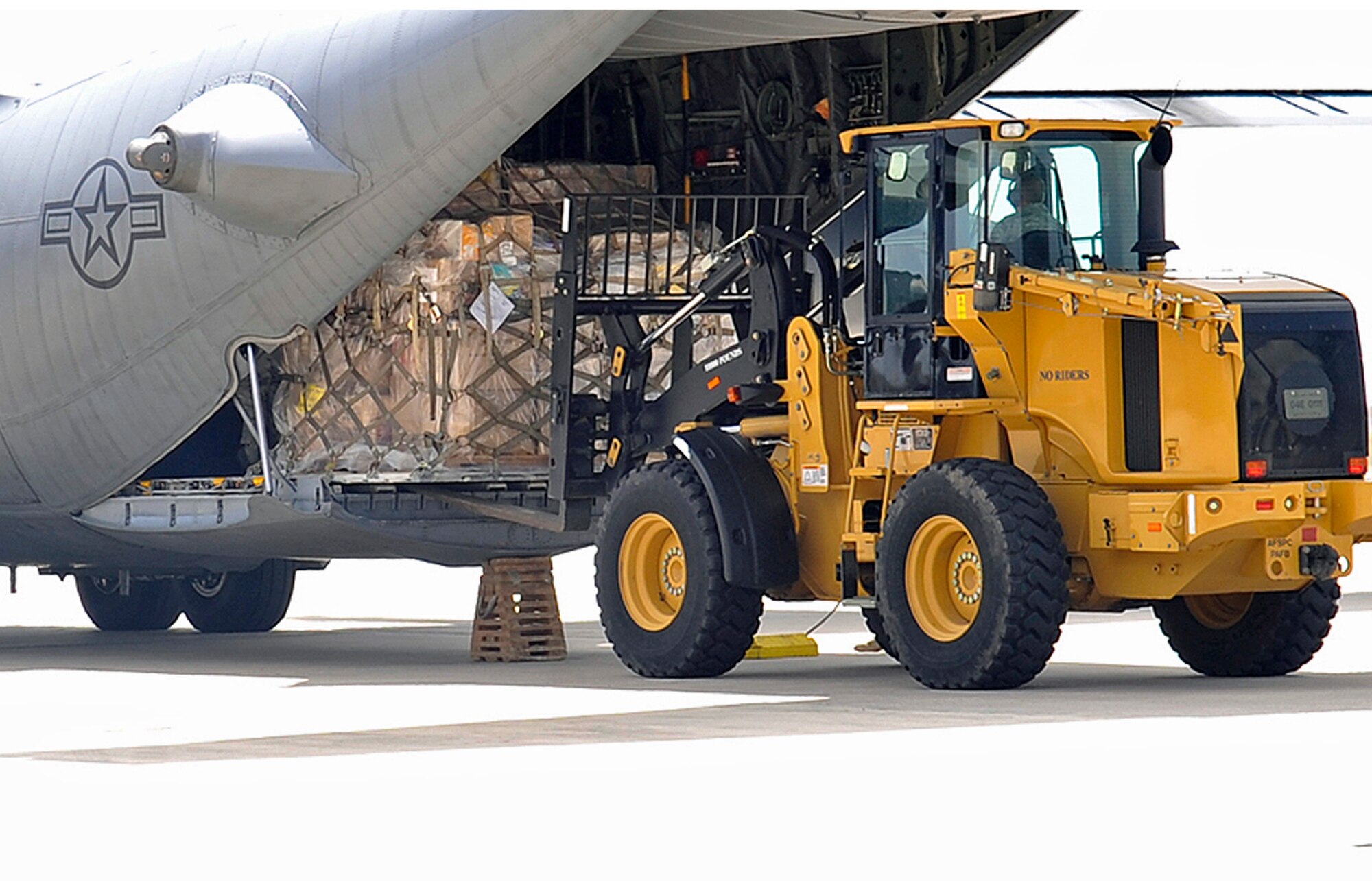 PETERSON AIR FORCE BASE, Colo. -- Airmen from the 21st Logistics Readiness Squadron and the 39th Aerial Port Squadron unload humanitarian assistance cargo April 13, 2011, on the Peterson Air Force Base flightline. About 40,000 pounds of relief aid, mostly coats and cold weather apparel, was donated by charitable organizations in Loveland, Colo. The pallets were unloaded as an engine running offload operation, typically used for tactical operations where time and ramp space are of critical importance, providing vital training for the LRS Airmen. The pallets will be loaded onto a KC-10 and sent to Charleston AFB, S.C., before making their way to Afghanistan. (U.S. Air Force photo/Rob Bussard)