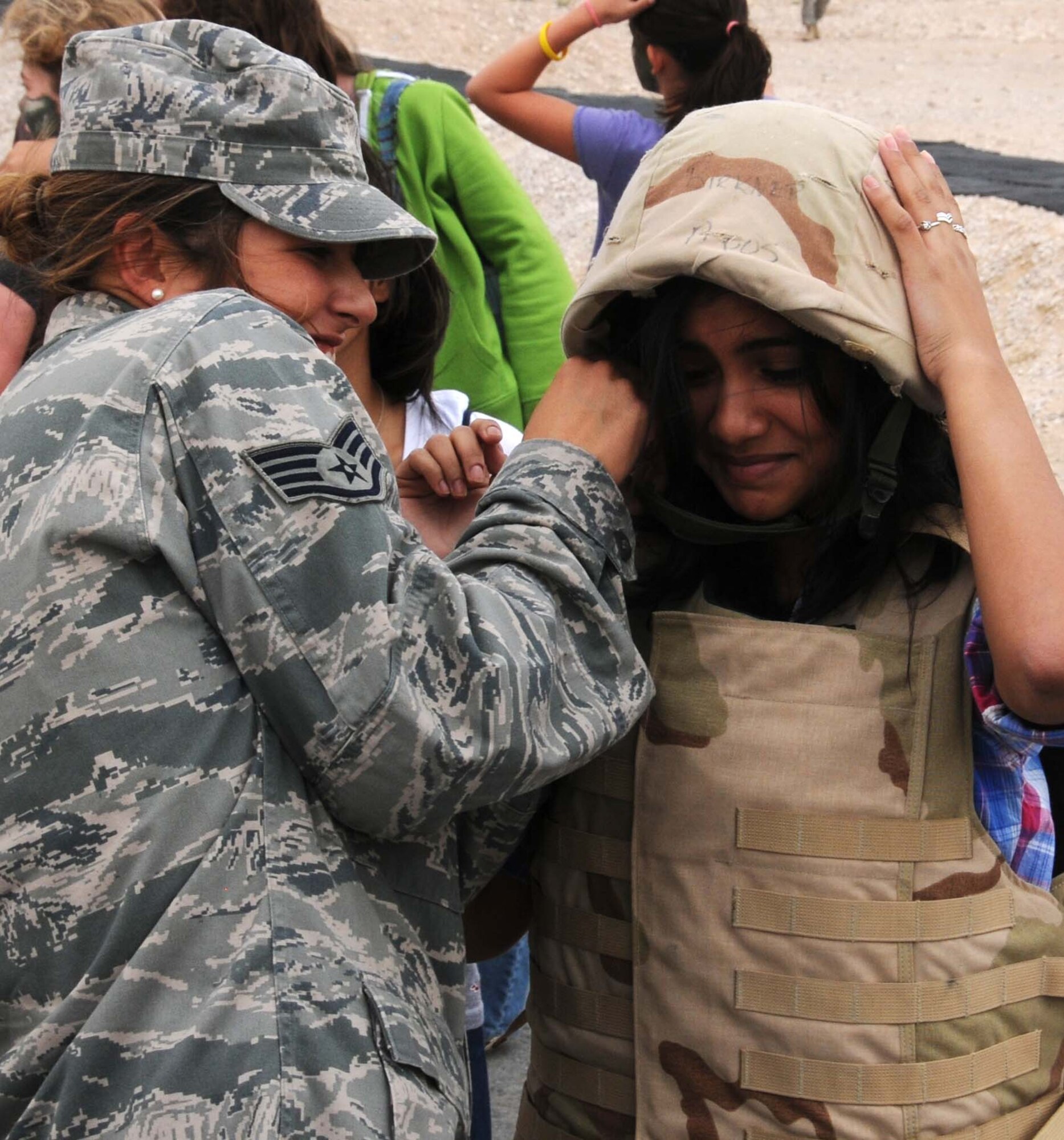 Staff Sgt Erica Benoit from the 379th Expeditionary Security Forces Squadron helps a student from the American School strap on a set of body armor. Airmen from the 379th Air Expeditionary Wing spent the day with the students participating in different activities. (U.S. Air Force photo/ Staff Sgt. Anthony Graham)