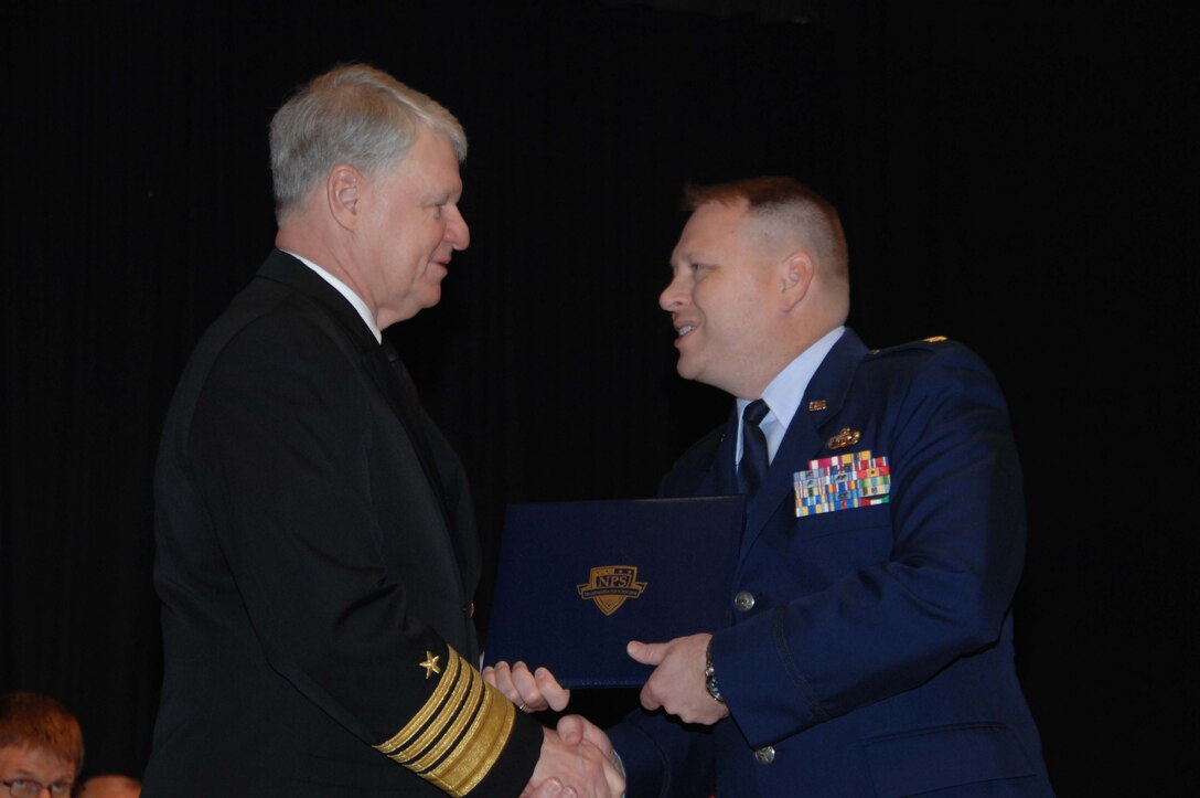 Chief of Naval Operations Adm. Gary Roughead presents Maj. Robert Cannon with a master’s degree during the graduation ceremony at the Naval Postgraduate School in Monterey, Calif., March 25. Major Cannon, the special security officer for Air Forces Northern, completed a rigorous 18-month program at NPS, earning a master’s degree in homeland defense and security. (Courtesy photo)